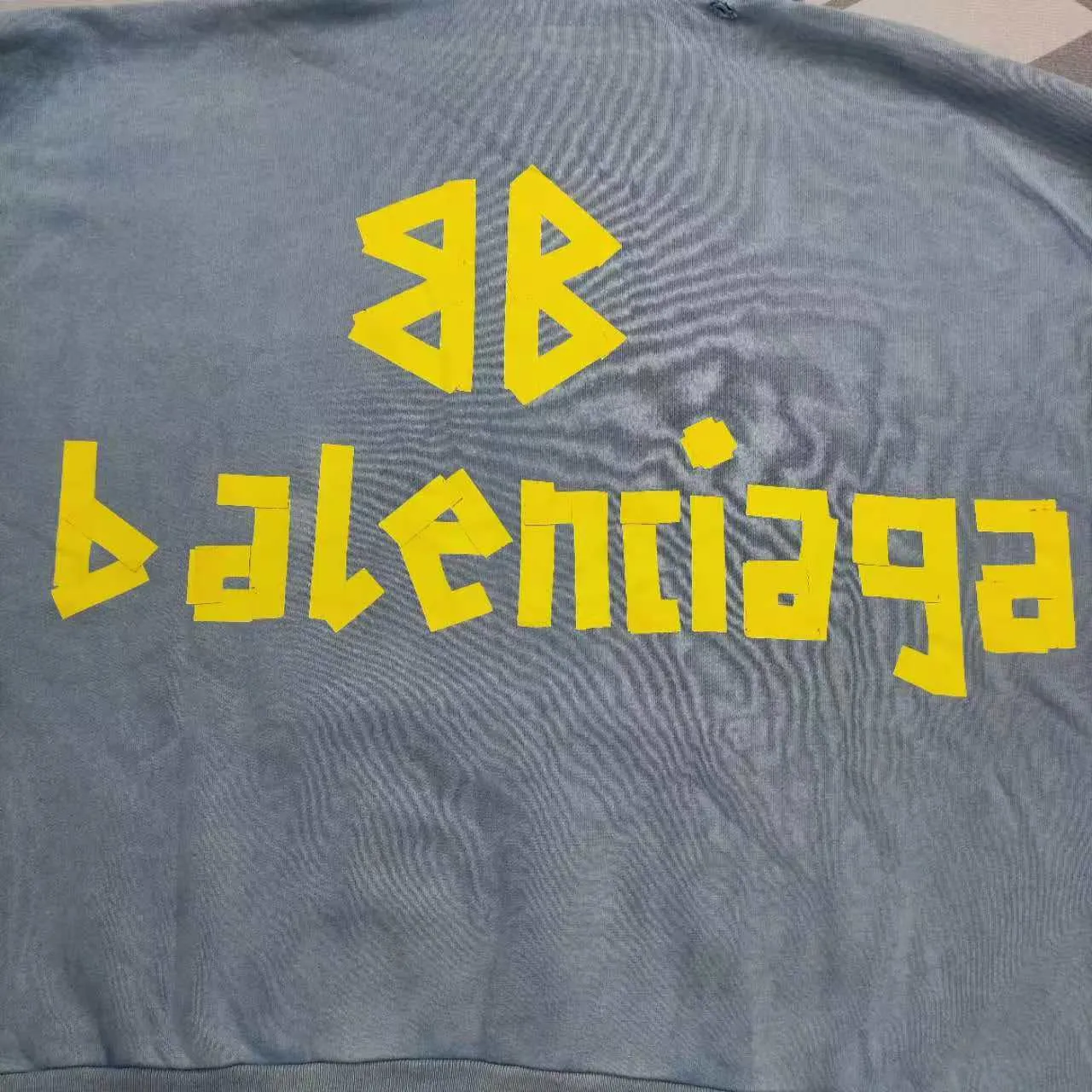 The top proven version of Balenciaga 23SS haze blue masking paper printed letters double-sided logo hooded loose hooded sweatshirt. This hoodie has a very interesting and cute design. The kangaroo pocket on the front of the large body is a reverse-cut design. The double side pockets are hollowed out, which actually deceives your vision when viewed from the front. The real pockets are sewn on the terry bottom on the reverse side. It is time-consuming and labor-intensive, but it is the core theme of the entire hoodie that cannot be ignored. In the same detail, the double side pockets are hemmed and stitched. And processed with holes; 480g heavy-weight pure cotton fabric with fine small terry bottom. After heavy mud dyeing and washing, the fabric still has a thick foundation and is comfortable and soft. The front and back double-sided textured paper transfer LOGO, and the front and back printing colors are different. The loose and large drop shoulder design is unisex. This style is also very suitable for girls to match. It is easy to create a lazy and casual street feel of the United States and France. Many holes are processed by hand grinding wheels on the body. Traces of muddying can be seen on the neckline, shoulder line, and side cuff splicing, but the visual effect transition is natural and soft without any sense of dirt. The old effect of the entire hoodie is excellent. The cuff threads are custom-woven in color; the packaging is washed and customized. The new gray silver letter main logo. The dropped shoulder model does not include shoulder width. The version is Kanye’s American style. Short and wide street casual version. From short sleeves to sweaters, this style is definitely not to be missed. Color: mud-dyed custom-woven navy Size: XS-S-M (Can be worn by both men and women, OS is loose and dropped on the shoulders) P:510