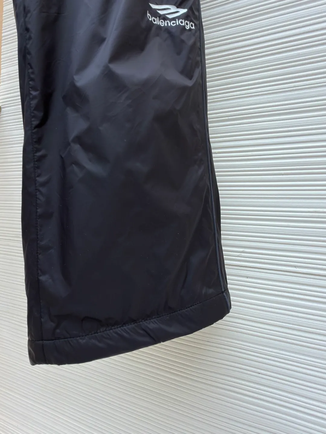 Balenciaga SKIWEAR series 3B printed fleece ski pants ●Original version: purchased and developed by 12414 ●Item number: 1682492-B25 ●Fabric: nylon fabric ●Technology: printing production ●Color: black ●Version: fitted version ●Weight: about 415 grams ●Size: S-M-L-XL ●Description: High-density technological nylon fiber is selected, and a delicate matte texture is created through a special textile process. The black tone presents a low-key and high-end visual effect. The fabric is lightweight yet stiff, has excellent wrinkle resistance and abrasion resistance, and is not prone to pilling or deformation for daily wear. It also has certain windproof properties to cope with changeable weather. The inner lining is made of high-density fluff material with excellent fluffiness and elasticity. When it closely fits the skin, it can form a layer of warm air, effectively locking in heat and improving the warmth factor of winter wear. The down fiber is delicate and smooth, avoiding the rough feeling of traditional plush fabrics, achieving the dual experience of "lightness and no burden" and "constant temperature and warmth", taking into account both comfort and practicality. Imported silicone printing technology is used on both sides of the trouser legs to present the iconic 3B sports icon pattern in a relief-like three-dimensional form. The silicone material has been pressed at high temperature and is tightly integrated with the fabric, making it difficult to fall off and crack. At the same time, it retains a delicate matte luster, forming a subtle texture contrast with the pants fabric, highlighting the brand recognition in a low-key manner. The mid-waist design is equipped with a double-layer elastic rib waistband and a built-in adjustable drawstring. The elastic fiber at the waistband has been pre-shrunk to ensure that it is not easy to loosen after long-term wear. It can not only stabilize the waist shape, but also adapt to the activity needs of different body shapes, taking into account sports functionality and daily comfort. The overall wiring is straight and delicate, the fabric is comfortable and soft, and the color is consistent without color difference. It can be matched with the same style to create a fashionable look and control various occasions. Customized accessories, complete with three standards, same style for men and women!