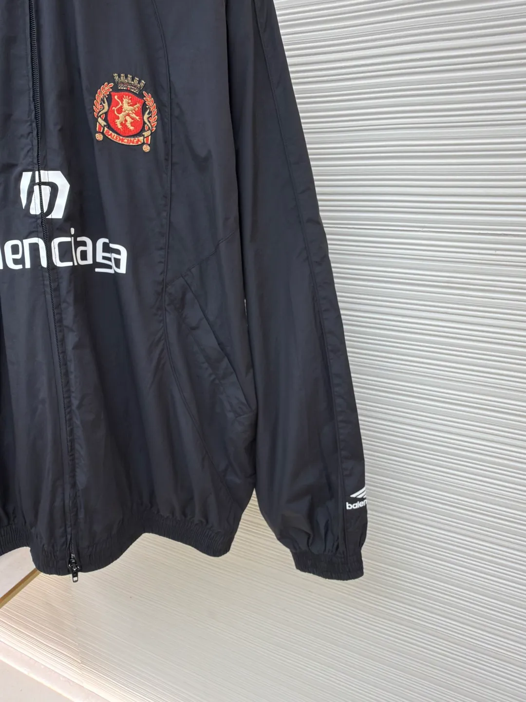 Balenciaga Manchester United co-branded No. 10 football jacket ●Authentic product: purchased and developed by 17699 ●Item number: 1680808-C65 ●Fabric: nylon fabric ●Technology: Printing ●Version: loose fit ●Size: 44-46-48-50 ●Description: Made of high-count and high-density nylon-cotton blended fabric. The lining is made of 32s combed cotton plain weave. The weight is 160g. It is embroidered by Tajima embroidery machine imported from Japan. The front panel + left and right sleeves are made of nylon material matte embroidery thread. The front and rear panels are made of DTF white ink heat transfer film material. The Y-plate pattern is scanned to make the pattern, and the material is cut by laser burning. The cut pieces are manually swept and positioned, and the front and back are hot-pressed with a high-temperature press machine to form. The letter composition on the front restores the flower effect, and the front and center are equipped with upper and lower rubber-threaded open-end zippers. Same style for men and women!