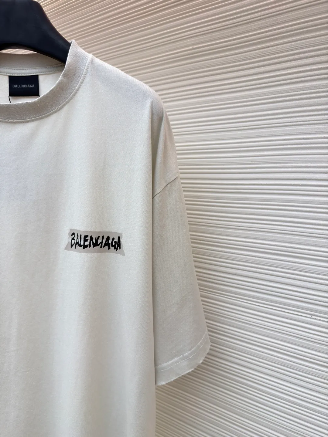 Balenciaga white background glue printed round neck short sleeves ●Original version: purchased and developed for 6500 ●Item number: 1681596-A15 ●Fabric: retro plain knitted fabric ●Technology: Glue printing production ●Color: white ●Version: fitted version ●Weight: about 255g ●Size: Thread, weight is 270g. The weight of the fabric ensures lightness and breathability. The 24-count yarn gives the fabric a delicate and smooth texture, and the plain knitted structure brings good skin-friendliness and moderate elasticity. The fabric has been washed in faded gray, which not only gives it a unique retro look and softens the color, but also achieves a pre-softening effect on the touch, eliminating the stiffness of new fabric and giving the garment a comfortable and soft old material feel when worn for the first time. Dark floral dot multi-layer overlay printing is an advanced printing technology that combines fine patterns and three-dimensional layers. Its core is to use high-mesh dot plate making to overprint transparent or light-colored printing paste on the fabric base multiple times with micron-level precision. Each overlay is accurately aligned to form a faint dark flower texture. The printing pattern does not rely on bright colors, but creates subtle light and shadow gradients and tactile layering on the surface of the fabric through the thickness difference of slurry accumulation and light refraction. The pattern shows subtle changes at different angles, combining visual depth and long-lasting washability. The overall wiring is straight and delicate, the fabric is comfortable and soft, and the color is consistent without color difference. It can be matched with the same style to create a fashionable look and control various occasions. Customized accessories, complete with three standards, same style for men and women!