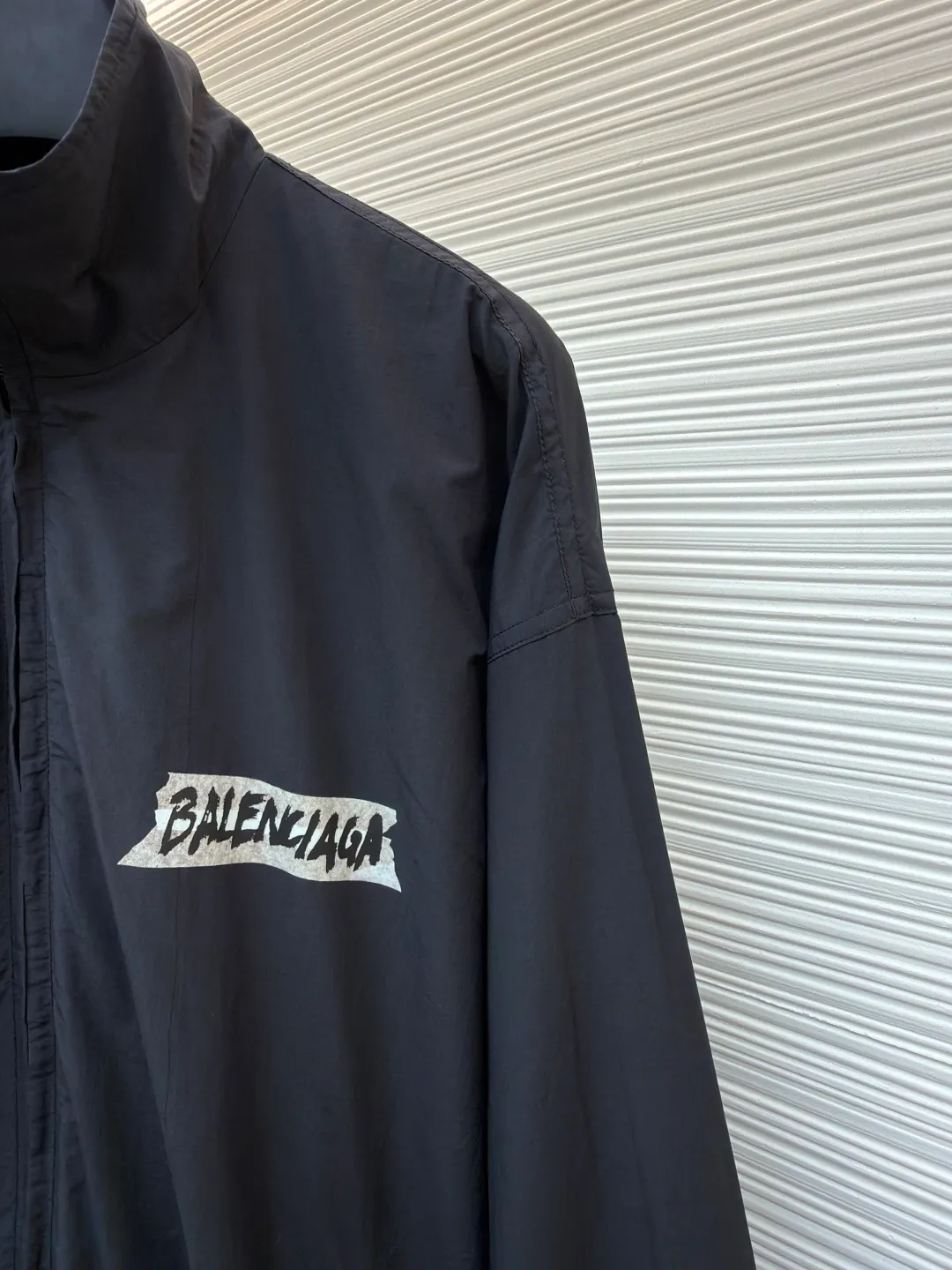 Balenciaga glue print jacket ●Original version: Purchased and developed for 20000 ●Item number: 1682403-B40 ●Fabric: woven nylon fabric ●Technology: glue printing production ●Color: black ●Version: fitted version ●Weight: about 480 grams ●Size: XS-S-M ●Description: This Balenciaga cotton blended jacket is made of 65% cotton and 35% polyester fiber blended fabric. It is first processed by a high-temperature pre-shrinking process to control the fabric shrinkage within 1% to avoid deformation after wearing and washing. The brand logo on the front of the body is made using glue printing technology. Before printing, the fabric is statically eliminated, and then the glue is tightly combined with the fabric through 150℃ high temperature printing. The pattern is clear, does not fall off and is friction-resistant. The jacket adopts a stand-up collar zipper design. The metal zipper has been treated with anti-oxidation plating and is smooth and easy to pull. The cuffs and hem are made of elastic ribbing. The rib weaving method is 1*1 double-needle technology, which is durable and not easy to loosen. The side seam pockets use invisible inlay technology with a stitch density of 8 stitches per centimeter. The shoulders are seamlessly taped. The overall craftsmanship takes into account the brand's iconic simple design and durability, and the details highlight the production standards of high-end clothing. The overall wiring is straight and delicate, the fabric is comfortable and soft, and the color is consistent without color difference. It can be matched with the same style to create a fashionable look and control various occasions. Customized accessories, complete with three standards, same style for men and women!