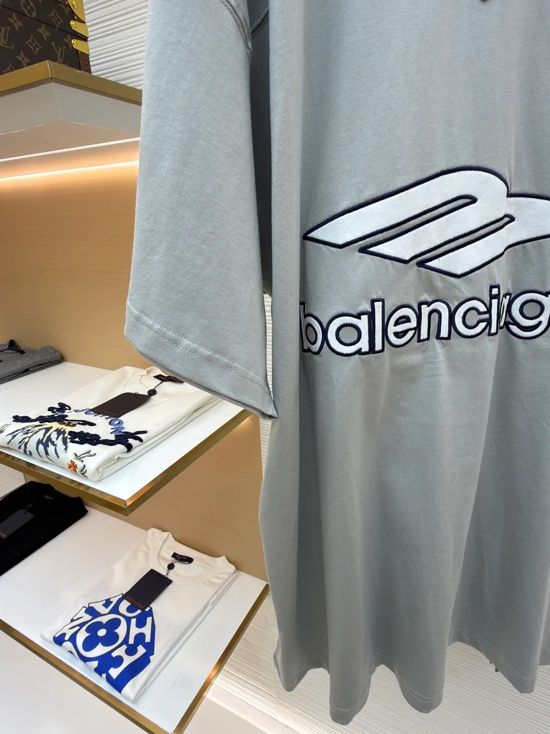 Balenciaga team series V-neck short sleeves ●Original version: Purchased and developed by 4417 ●Item number: 1682335-A60 ●Fabric: plain knitted compact cotton fabric ●Technology: glue printing ●Color: gray ●Version: loose version ●Weight: about 315 grams ●Size: XS-S-M-L ●Description: The main body is made of 24-count special woven compact cotton with a weight of 185g/㎡. Compact spinning technology is applied in the spinning process, which significantly reduces yarn hairiness and makes the yarn smoother and stronger. This gives the fabric an unusually dense structure, a smooth and smooth surface, and excellent pilling resistance, while retaining the softness and breathability of pure cotton. The weight of 185g is light to middleweight, ensuring that the clothing is light, drapeable and can move freely. It is very suitable for creating a long-sleeved shirt that combines sportiness with daily comfort. The V-neck part is made of two different colors of high-elastic rib fabrics. The process step is to first weave ribbed belts of two colors separately, and then through precise cutting and splicing, form a V-shaped neckline with sharp color contrast. It breaks the monotony of the solid color body, uses strong color contrast to create a young and energetic visual focus, and optimizes the neck line. The pattern is pre-cut and formed into patches on fabrics of different materials or colors, and then covered on the body. Finally, high-density embroidery thread is used to fix the edges and outline the internal details. Its function is to create patterns with bright colors, strong texture contrast, three-dimensionality and durability. The edges of the pattern are strong and not easy to wear. A special elastic paste is screen-printed on the sleeves to create brightly colored patterns with a slightly coated feel. The elastic paste ensures that the printed area can stretch with the fabric without cracking. It forms a texture contrast between one flat and one convex with the three-dimensional sense of appliqué, which increases the interest and complexity of the design. The overall wiring is straight and delicate, the fabric is comfortable and soft, and the color is consistent without color difference. It can be matched with the same style to create a fashionable look and control various occasions. Customized accessories, complete with three standards, same style for men and women!