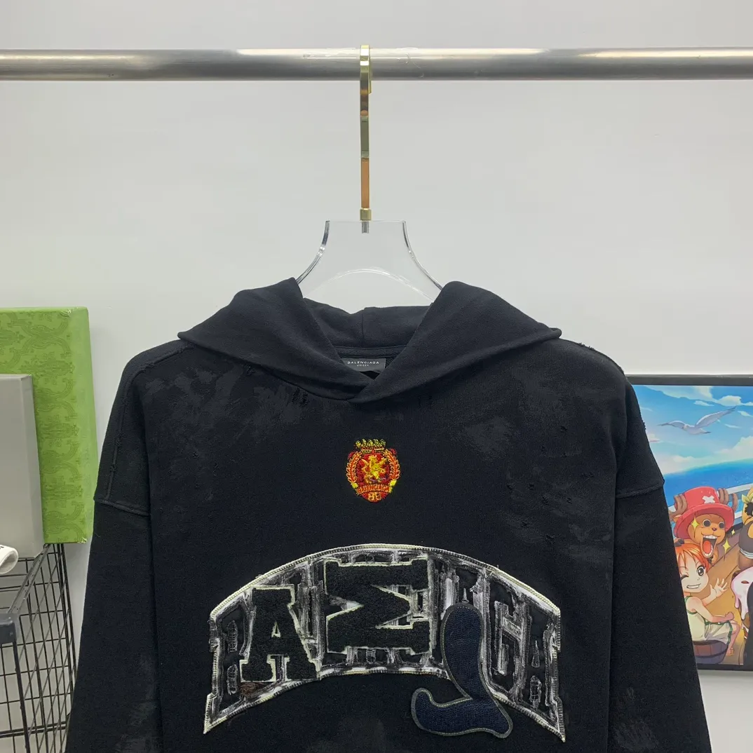 Top tested version 23FW BALENCIAGA Paris Manchester United limited edition distressed male and female couple star same style pure cotton loose hooded sweatshirt [very suitable for Douyin, and other platforms! The letters in the LOGO position have been damaged and polished! 】 The fabric is custom-made washed knitted cotton terry material. The upper body is very soft. The front panel uses a classic hand pocket with a worn effect. The overall yellow and dirty effect is all artificially sprayed with majolica. It requires proficiency and experience to achieve this natural and elegant effect!  Customized towel embroidery on the chest, heavily damaged! The aging effect is very obvious! The overall artificial positioning coating is hand-made, washed and dirty. The frayed hole craftsmanship has a hand-painted graffiti effect. The arms behind the bend are made of open-stitch frayed craftsmanship. The wiring is delicate. Elastic cuff design. The whole body is hand-positioned with muddy dyeing and frayed effect! Ready-made garments are washed twice with water +➕ once with wax. It feels smooth!   The Manchester United letters and logo on the chest are designed with full embroidery and the details are visible!  Size: XS-L Color: White Black P: 470