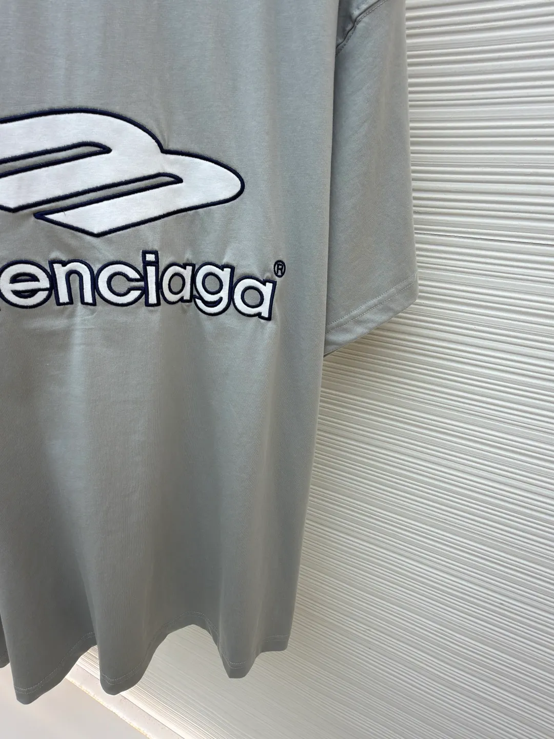 Balenciaga team series V-neck short sleeves ●Original version: Purchased and developed by 4417 ●Item number: 1682335-A60 ●Fabric: plain knitted compact cotton fabric ●Technology: glue printing ●Color: gray ●Version: loose version ●Weight: about 315 grams ●Size: XS-S-M-L ●Description: The main body is made of 24-count special woven compact cotton with a weight of 185g/㎡. Compact spinning technology is applied in the spinning process, which significantly reduces yarn hairiness and makes the yarn smoother and stronger. This gives the fabric an unusually dense structure, a smooth and smooth surface, and excellent pilling resistance, while retaining the softness and breathability of pure cotton. The weight of 185g is light to middleweight, ensuring that the clothing is light, drapeable and can move freely. It is very suitable for creating a long-sleeved shirt that combines sportiness with daily comfort. The V-neck part is made of two different colors of high-elastic rib fabrics. The process step is to first weave ribbed belts of two colors separately, and then through precise cutting and splicing, form a V-shaped neckline with sharp color contrast. It breaks the monotony of the solid color body, uses strong color contrast to create a young and energetic visual focus, and optimizes the neck line. The pattern is pre-cut and formed into patches on fabrics of different materials or colors, and then covered on the body. Finally, high-density embroidery thread is used to fix the edges and outline the internal details. Its function is to create patterns with bright colors, strong texture contrast, three-dimensionality and durability. The edges of the pattern are strong and not easy to wear. A special elastic paste is screen-printed on the sleeves to create brightly colored patterns with a slightly coated feel. The elastic paste ensures that the printed area can stretch with the fabric without cracking. It forms a texture contrast between one flat and one convex with the three-dimensional sense of appliqué, which increases the interest and complexity of the design. The overall wiring is straight and delicate, the fabric is comfortable and soft, and the color is consistent without color difference. It can be matched with the same style to create a fashionable look and control various occasions. Customized accessories, complete with three standards, same style for men and women!