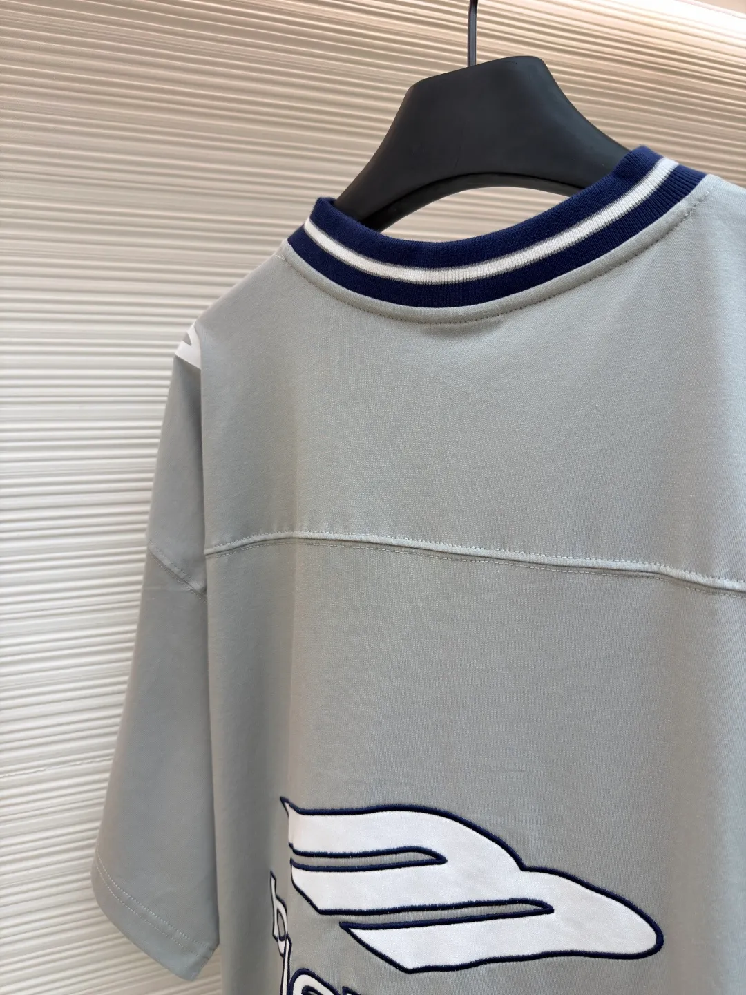 Balenciaga team series V-neck short sleeves ●Original version: Purchased and developed by 4417 ●Item number: 1682335-A60 ●Fabric: plain knitted compact cotton fabric ●Technology: glue printing ●Color: gray ●Version: loose version ●Weight: about 315 grams ●Size: XS-S-M-L ●Description: The main body is made of 24-count special woven compact cotton with a weight of 185g/㎡. Compact spinning technology is applied in the spinning process, which significantly reduces yarn hairiness and makes the yarn smoother and stronger. This gives the fabric an unusually dense structure, a smooth and smooth surface, and excellent pilling resistance, while retaining the softness and breathability of pure cotton. The weight of 185g is light to middleweight, ensuring that the clothing is light, drapeable and can move freely. It is very suitable for creating a long-sleeved shirt that combines sportiness with daily comfort. The V-neck part is made of two different colors of high-elastic rib fabrics. The process step is to first weave ribbed belts of two colors separately, and then through precise cutting and splicing, form a V-shaped neckline with sharp color contrast. It breaks the monotony of the solid color body, uses strong color contrast to create a young and energetic visual focus, and optimizes the neck line. The pattern is pre-cut and formed into patches on fabrics of different materials or colors, and then covered on the body. Finally, high-density embroidery thread is used to fix the edges and outline the internal details. Its function is to create patterns with bright colors, strong texture contrast, three-dimensionality and durability. The edges of the pattern are strong and not easy to wear. A special elastic paste is screen-printed on the sleeves to create brightly colored patterns with a slightly coated feel. The elastic paste ensures that the printed area can stretch with the fabric without cracking. It forms a texture contrast between one flat and one convex with the three-dimensional sense of appliqué, which increases the interest and complexity of the design. The overall wiring is straight and delicate, the fabric is comfortable and soft, and the color is consistent without color difference. It can be matched with the same style to create a fashionable look and control various occasions. Customized accessories, complete with three standards, same style for men and women!