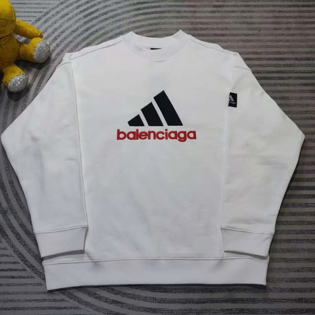 [New arrival] Balenciaga x Adidas joint logo embroidered round neck sweatshirt. The embroidery is embroidered with an imported Tajima embroidery machine, with a three-dimensional effect. Clear lines. No rough edges and miscellaneous threads. Ultra-high-tech embroidery. It uses 26 counts of combed cotton + 10 counts of 100% cotton. The gram weight is 480g. The fabric is made of high-quality domestic Xinjiang cotton yarn. Xinjiang cotton is recognized as a superior material among domestic cotton. The fabric is woven with the internationally recognized Fukuhara knitting machine. The fabric has clear texture, good resilience, strong wrinkle resistance, good wear resistance and breathability, and is close to the skin. It is not easy to loosen and has a long-lasting widening effect. The fabric has good gloss, strength, good wear resistance, low shrinkage, and a good skeleton feel. The pure cotton cloth is produced by air flow liquid cylinder. The environmentally friendly dyeing meets the national first-class product requirements. It is not easy to fade and is not prone to creases and claw marks. The version is well-fitting and can be worn all year round. The sewing machine needle uses No. 9 round-headed needles. It does not puncture or break the fibers of the fabric. The density of the thread is 3CM/14 needles. It is tight, not loose and not sparse. The sewing thread uses imported oil-proof treated thread, and there will be no oil stains. Kanche is imported with a silver sword and does not eat cloth. No more fabric left, full brand and high-quality feel Color: White Size: 1-4 P:450