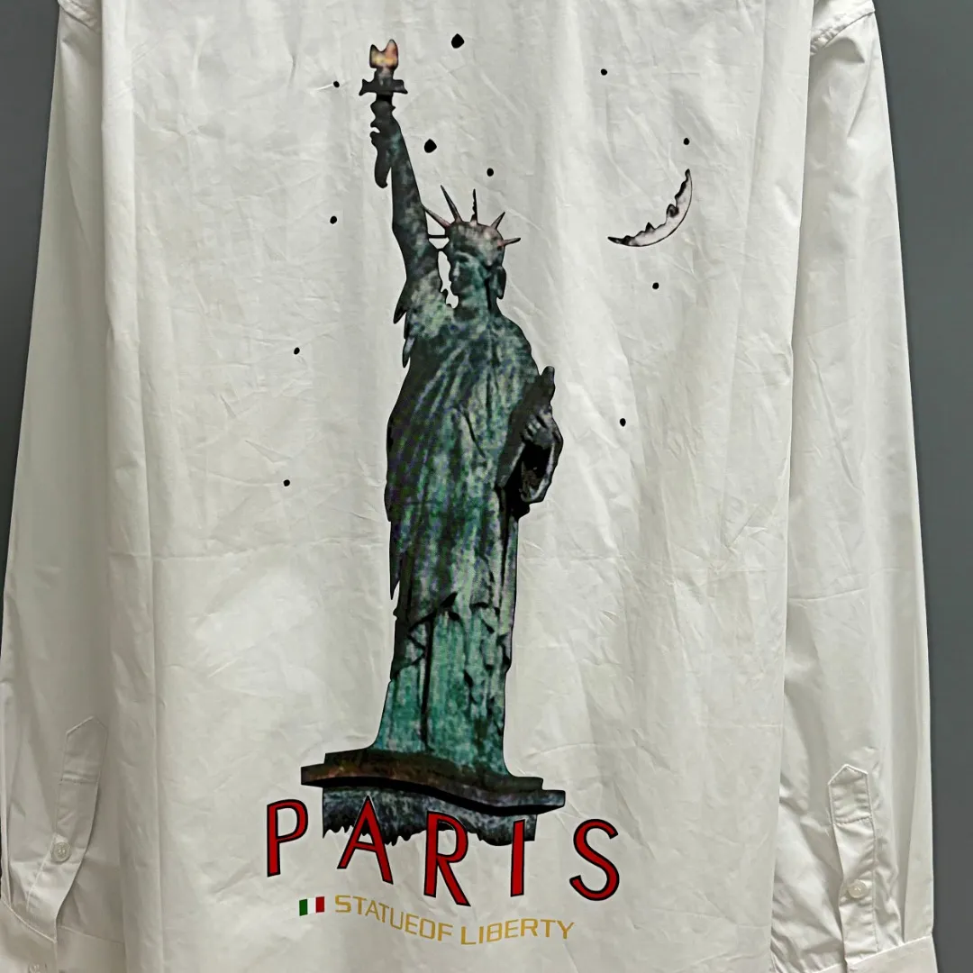 🅿️220 BALENCIAGA/Balenciaga early autumn printed embroidered shirt. Customized classic 40-count plain weave imitation Tencel Paris shirt fabric. Loose fit and three-dimensional upper body. Smooth and natural lines from shoulder line to waistline to hem. Smooth transition of lines. No unnecessary folds or accumulation. The whole body is neat and stretched. Customized Paris logo engraved buttons. Embroidery of Paris letters on the chest. Precise stitching. Silky threading. Paired with large-area printing of the Statue of Liberty on the back. The effect is three-dimensional. The printing fits perfectly with the fabric, and there will be no problems such as color fading, peeling off, etc. Size: S M L XL