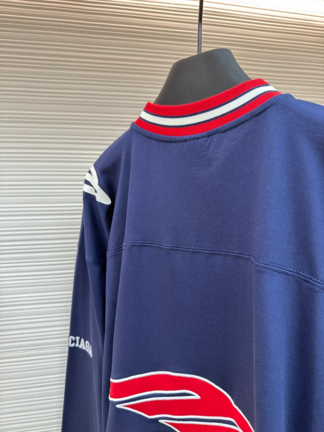 Balenciaga team series V-neck long sleeves ●Original version: purchased and developed by 8016 ●Item number: 1682072-A55 ●Fabric: plain knitted compact cotton fabric ●Technology: glue printing ●Color: blue ●Version: loose version ●Weight: about 375 grams ●Size: XS-S-M-L ●Description: The main body is made of 24-count special woven compact cotton with a weight of 185g/㎡. Compact spinning technology is applied in the spinning process, which significantly reduces yarn hairiness and makes the yarn smoother and stronger. This gives the fabric an unusually dense structure, a smooth and smooth surface, and excellent pilling resistance, while retaining the softness and breathability of pure cotton. The weight of 185g is light to middleweight, ensuring that the clothing is light, drapeable and can move freely. It is very suitable for creating a long-sleeved shirt that combines sportiness with daily comfort. The V-neck part is made of two different colors of high-elastic rib fabrics. The process step is to first weave ribbed belts of two colors separately, and then through precise cutting and splicing, form a V-shaped neckline with sharp color contrast. It breaks the monotony of the solid color body, uses strong color contrast to create a young and energetic visual focus, and optimizes the neck line. The pattern is pre-cut and formed into patches on fabrics of different materials or colors, and then covered on the body. Finally, high-density embroidery thread is used to fix the edges and outline the internal details. Its function is to create patterns with bright colors, strong texture contrast, three-dimensionality and durability. The edges of the pattern are strong and not easy to wear. A special elastic paste is screen-printed on the sleeves to create brightly colored patterns with a slightly coated feel. The elastic paste ensures that the printed area can stretch with the fabric without cracking. It forms a texture contrast between one flat and one convex with the three-dimensional sense of appliqué, which increases the interest and complexity of the design. The overall wiring is straight and delicate, the fabric is comfortable and soft, and the color is consistent without color difference. It can be matched with the same style to create a fashionable look and control various occasions. Customized accessories, complete with three standards, same style for men and women!