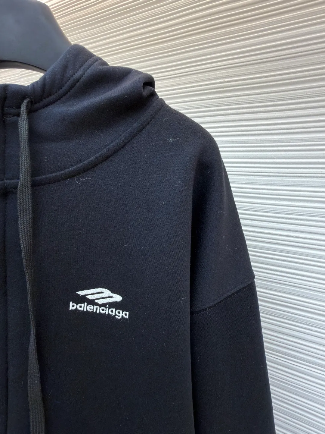 Balenciaga SIK WEAR ski series velvet hooded sweatshirt ●Original version: purchased and developed for 9999 ●Item number: 1681932-B15 ●Fabric: velvet fabric ●Technology: embroidery production ●Color: black ●Version: loose fit ●Weight: about 945 grams ●Size: XS-S-M-L ●Description: It adopts a high-count and high-density plain knitting structure. The surface shows an extremely delicate and smooth texture, giving the garment a low-key and high-end matte texture. This is in sharp contrast to traditional heavy and fluffy ski suits, achieving a balance between "light weight" and "excellent performance." After being treated with Teflon coating, the surface of the fabric can resist being soaked by snow water, while maintaining a certain degree of breathability to avoid accumulation of sweat inside. The fabric may also be tear-resistant and have some elasticity to ensure freedom of movement and durability during skiing. The interior is made of velvet material. By creating a large number of tiny air traps on its surface, a layer of still air is formed, which effectively locks body heat and achieves excellent warmth retention. The materials selected focus on skin-friendly feeling to avoid the itching that may be caused by ordinary thermal insulation materials. At the same time, excellent fleece has quick-drying properties, which can quickly export internal moisture to the outer layer for evaporation, keeping the skin dry and comfortable. It is perfect for the micro-environment of alternating hot and cold conditions when skiing. Zippers are not commercially available, but "customized rubber zippers" specially developed for the SIKWEAR series. Its teeth are treated with high-performance polymer or rubber to ensure they are smooth and durable in extremely cold environments and are not easy to freeze. The design of the zipper puller must also be ergonomically considered to facilitate operation when wearing gloves. Customized jacquard webbing, jacquard weaving technology can create clear, three-dimensional and never fall off patterns, its texture and firmness are far better than ordinary printing. This webbing becomes the main visual axis that runs through the front of the garment, making it highly recognizable. The letters are finished with Tajima embroidery. The effect is far superior to ordinary computer embroidery. It is characterized by extremely dense and even stitches, clear and sharp edges, and full and three-dimensional patterns. The direction and tension of each stitch are precisely controlled to ensure that the logo remains in perfect shape under any wearing condition and will not wrinkle or deform. The rich texture and luster brought about by this craftsmanship are core expressions of luxury identity. SIKWEAR velvet hooded sweatshirt is a piece of clothing art that integrates cutting-edge technological fabrics, sophisticated functional design, luxurious custom details and palace-level craftsmanship. It breaks the boundaries between professional ski wear and everyday fashion, creating a complete narrative about modern luxury sportswear. It's more than just a sweatshirt for keeping warm, it's a piece of equipment for connoisseurs who pursue ultimate performance and top-notch fashion. The overall wiring is straight and delicate, the fabric is comfortable and soft, and the color is consistent without color difference. It can be matched with the same style to create a fashionable look and control various occasions. Customized accessories, complete with three standards, same style for men and women!