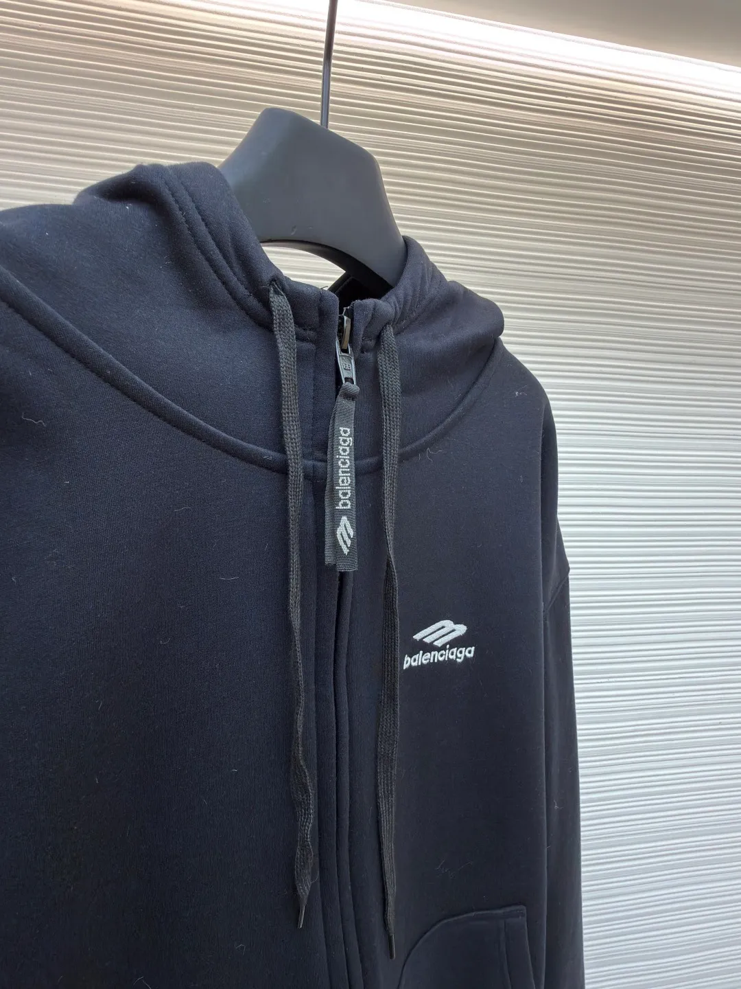 Balenciaga SIK WEAR ski series velvet hooded sweatshirt ●Original version: purchased and developed for 9999 ●Item number: 1681932-B15 ●Fabric: velvet fabric ●Technology: embroidery production ●Color: black ●Version: loose fit ●Weight: about 945 grams ●Size: XS-S-M-L ●Description: It adopts a high-count and high-density plain knitting structure. The surface shows an extremely delicate and smooth texture, giving the garment a low-key and high-end matte texture. This is in sharp contrast to traditional heavy and fluffy ski suits, achieving a balance between "light weight" and "excellent performance." After being treated with Teflon coating, the surface of the fabric can resist being soaked by snow water, while maintaining a certain degree of breathability to avoid accumulation of sweat inside. The fabric may also be tear-resistant and have some elasticity to ensure freedom of movement and durability during skiing. The interior is made of velvet material. By creating a large number of tiny air traps on its surface, a layer of still air is formed, which effectively locks body heat and achieves excellent warmth retention. The materials selected focus on skin-friendly feeling to avoid the itching that may be caused by ordinary thermal insulation materials. At the same time, excellent fleece has quick-drying properties, which can quickly export internal moisture to the outer layer for evaporation, keeping the skin dry and comfortable. It is perfect for the micro-environment of alternating hot and cold conditions when skiing. Zippers are not commercially available, but "customized rubber zippers" specially developed for the SIKWEAR series. Its teeth are treated with high-performance polymer or rubber to ensure they are smooth and durable in extremely cold environments and are not easy to freeze. The design of the zipper puller must also be ergonomically considered to facilitate operation when wearing gloves. Customized jacquard webbing, jacquard weaving technology can create clear, three-dimensional and never fall off patterns, its texture and firmness are far better than ordinary printing. This webbing becomes the main visual axis that runs through the front of the garment, making it highly recognizable. The letters are finished with Tajima embroidery. The effect is far superior to ordinary computer embroidery. It is characterized by extremely dense and even stitches, clear and sharp edges, and full and three-dimensional patterns. The direction and tension of each stitch are precisely controlled to ensure that the logo remains in perfect shape under any wearing condition and will not wrinkle or deform. The rich texture and luster brought about by this craftsmanship are core expressions of luxury identity. SIKWEAR velvet hooded sweatshirt is a piece of clothing art that integrates cutting-edge technological fabrics, sophisticated functional design, luxurious custom details and palace-level craftsmanship. It breaks the boundaries between professional ski wear and everyday fashion, creating a complete narrative about modern luxury sportswear. It's more than just a sweatshirt for keeping warm, it's a piece of equipment for connoisseurs who pursue ultimate performance and top-notch fashion. The overall wiring is straight and delicate, the fabric is comfortable and soft, and the color is consistent without color difference. It can be matched with the same style to create a fashionable look and control various occasions. Customized accessories, complete with three standards, same style for men and women!
