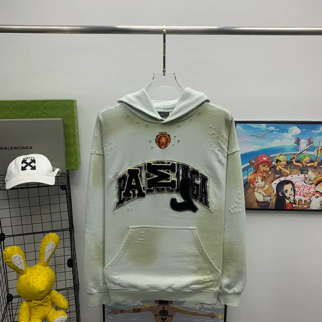 Top tested version 23FW BALENCIAGA Paris Manchester United limited edition distressed male and female couple star same style pure cotton loose hooded sweatshirt [very suitable for Douyin, and other platforms! The letters in the LOGO position have been damaged and polished! 】 The fabric is custom-made washed knitted cotton terry material. The upper body is very soft. The front panel uses a classic hand pocket with a worn effect. The overall yellow and dirty effect is all artificially sprayed with majolica. It requires proficiency and experience to achieve this natural and elegant effect!  Customized towel embroidery on the chest, heavily damaged! The aging effect is very obvious! The overall artificial positioning coating is hand-made, washed and dirty. The frayed hole craftsmanship has a hand-painted graffiti effect. The arms behind the bend are made of open-stitch frayed craftsmanship. The wiring is delicate. Elastic cuff design. The whole body is hand-positioned with muddy dyeing and frayed effect! Ready-made garments are washed twice with water +➕ once with wax. It feels smooth!   The Manchester United letters and logo on the chest are designed with full embroidery and the details are visible!  Size: XS-L Color: White Black P: 470