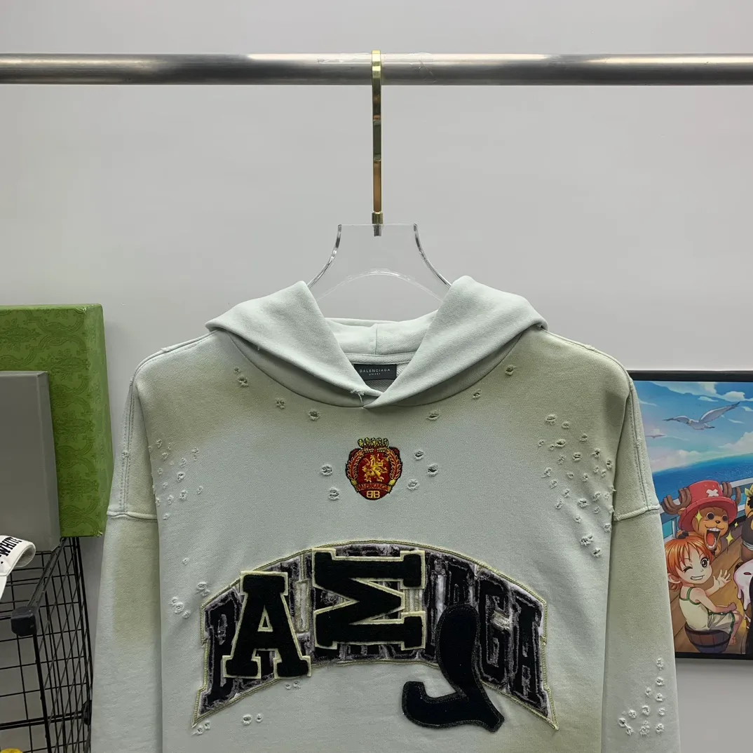 Top tested version 23FW BALENCIAGA Paris Manchester United limited edition distressed male and female couple star same style pure cotton loose hooded sweatshirt [very suitable for Douyin, and other platforms! The letters in the LOGO position have been damaged and polished! 】 The fabric is custom-made washed knitted cotton terry material. The upper body is very soft. The front panel uses a classic hand pocket with a worn effect. The overall yellow and dirty effect is all artificially sprayed with majolica. It requires proficiency and experience to achieve this natural and elegant effect!  Customized towel embroidery on the chest, heavily damaged! The aging effect is very obvious! The overall artificial positioning coating is hand-made, washed and dirty. The frayed hole craftsmanship has a hand-painted graffiti effect. The arms behind the bend are made of open-stitch frayed craftsmanship. The wiring is delicate. Elastic cuff design. The whole body is hand-positioned with muddy dyeing and frayed effect! Ready-made garments are washed twice with water +➕ once with wax. It feels smooth!   The Manchester United letters and logo on the chest are designed with full embroidery and the details are visible!  Size: XS-L Color: White Black P: 470