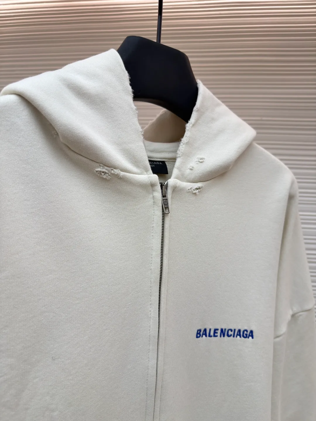Balenciaga letter embroidered hooded zipper long-sleeved sweatshirt ●Original version: Purchased and developed for 9200 ●Item number: 1682263-A95 ●Fabric: combed cotton ●Technology: Washed and frayed ●Color: white ●Version: loose fit ●Weight: about 965 grams ●Size: S-M-L ●Description: This Balenciaga letter embroidered hooded zipper sweatshirt is made of 380g heavyweight pure cotton terry cloth, which has been treated with enzyme washing process. The fabric has a natural old-fashioned soft and waxy texture. At the same time, the stone grinding process is used to create irregular raw edge effects on the cuffs and hem, restoring the retro street style. The body adopts a loose, dropped-shoulder version, and the three-dimensional tailoring makes the shoulder lines smooth. The hooded part has a built-in drawstring made of pure cotton and is pre-shrunk to prevent it from deforming. The custom-made metal zipper on the front zipper closes smoothly and has no lag after repeated opening and closing tests. The brand letters on the left chest are made with imported embroidery machines using flat embroidery stitches, using polyester thread with high color fastness. The stitches are fine and neat without skipping, and the letter outline is three-dimensional and clear. The overall stitching uses double-needle overlocking technology, with up to 12 stitches per inch. The ribbed edges on the cuffs and hem are made of spandex blended material, which has long-lasting elasticity and is not easy to loosen, taking into account both wearing comfort and stiffness. The overall wiring is straight and delicate, the fabric is comfortable and soft, and the color is consistent without color difference. It can be matched with the same style to create a fashionable look and control various occasions. Customized accessories, complete with three standards, same style for men and women!