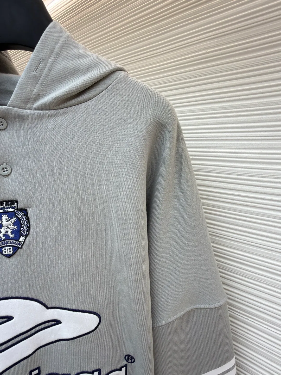 Balenciaga 3B football Polo hoodie ●Original version: purchased and developed by 10767 ●Item number: 1682334-B05 ●Fabric: cotton fabric ●Technology: embroidery applique production ●Color: gray ●Version: loose fit ●Weight: about 885 grams ●Size: XS-S-M-L ●Description: The neckline adopts a half-open button design and is decorated with metal badges to enhance the layered look; the main body of the garment presents the brand logo through three-dimensional foam printing technology, and the grayscale gradient effect enhances the visual texture. The cuffs and hem are edged with contrasting ribbing, which has moderate elasticity and is not easily deformed; a collage label is embedded in the left hem, and the details echo the brand's street style. The partial logo embroidery on the shoulders and cuffs echoes the main pattern. The overall craftsmanship takes into account practical wearability and brand recognition, making it suitable for daily casual or trendy looks. The overall wiring is straight and delicate, the fabric is comfortable and soft, and the color is consistent without color difference. It can be matched with the same style to create a fashionable look and control various occasions. Customized accessories, complete with three standards, same style for men and women!