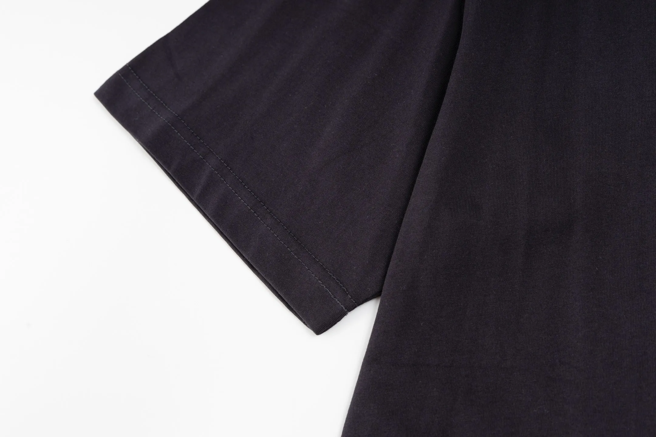 🅿️290 [Exclusive supply] BLCG 25FW badge printed short sleeves (black) The fabric is made of 24S 185g double yarn special textile compact cotton, and the rib is made of 32S 340g double yarn stretch rib. The structure of pure cotton fabric is plain weave. The surface of the fabric is smooth and delicate, and the texture is tight. It has good moisture absorption, breathability and comfort, and can keep you dry and comfortable. Due to its tight spinning process, it also has good wrinkle resistance and durability, making it suitable for long-term wear or use. The multi-layer superposition process of dark flower paste dots uses precision screen technology to cover the fabric with translucent printing paste through multiple layered printing. Each layer is laminated and fused with micron-level tolerances. Through subtle changes in the thickness and density of the slurry, an invisible pattern with a transition between dark and light is formed on the surface of the fabric. This technology replaces color contrast with physical accumulation, and uses the diffuse reflection of light on concave and convex surfaces to present a looming light and shadow relief effect, creating a high-end print with both visual haziness and tactile three-dimensionality, which perfectly fits the low-key and luxurious design aesthetics. Size:XS-S-M-L