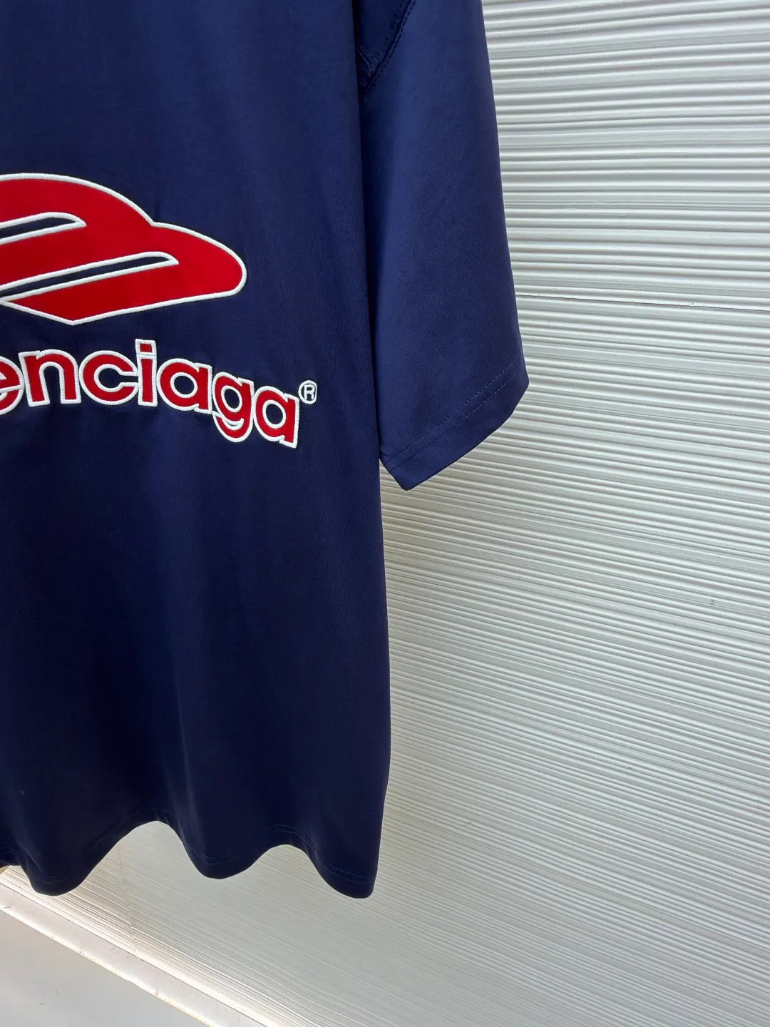 Balenciaga team series V-neck short sleeves ●Original version: Purchased and developed for 5699 ●Item number: 1682041-A50 ●Fabric: plain knitted compact cotton fabric ●Technology: glue printing ●Color: blue ●Version: loose version ●Weight: about 300 grams ●Size: Compact spinning technology is applied in the spinning process, which significantly reduces yarn hairiness and makes the yarn smoother and stronger. This gives the fabric an unusually dense structure, a smooth and smooth surface, and excellent pilling resistance, while retaining the softness and breathability of pure cotton. The weight of 185g is light to middleweight, ensuring that the clothing is light, drapeable and can move freely. It is very suitable for creating a long-sleeved shirt that combines sportiness with daily comfort. The V-neck part is made of two different colors of high-elastic rib fabrics. The process step is to first weave ribbed belts of two colors separately, and then through precise cutting and splicing, form a V-shaped neckline with sharp color contrast. It breaks the monotony of the solid color body, uses strong color contrast to create a young and energetic visual focus, and optimizes the neck line. The pattern is pre-cut and formed into patches on fabrics of different materials or colors, and then covered on the body. Finally, high-density embroidery thread is used to fix the edges and outline the internal details. Its function is to create patterns with bright colors, strong texture contrast, three-dimensionality and durability. The edges of the pattern are strong and not easy to wear. A special elastic paste is screen-printed on the sleeves to create brightly colored patterns with a slightly coated feel. The elastic paste ensures that the printed area can stretch with the fabric without cracking. It forms a texture contrast between one flat and one convex with the three-dimensional sense of appliqué, which increases the interest and complexity of the design. The overall wiring is straight and delicate, the fabric is comfortable and soft, and the color is consistent without color difference. It can be matched with the same style to create a fashionable look and control various occasions. Customized accessories, complete with three standards, same style for men and women!
