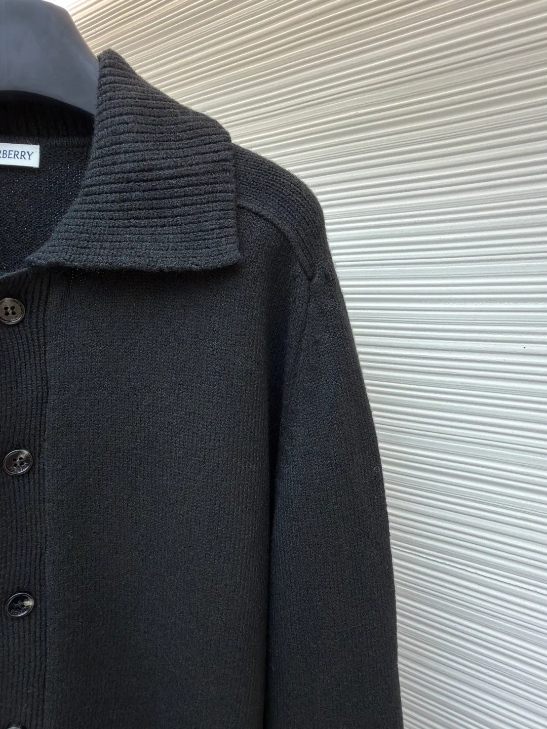 Burberry lapel rib knitted cashmere sweater ●Original version: purchased and developed by 11575 ●Item number: 1682226-B15 ●Fabric: wool blended fabric ●Technology: knitted ●Color: black ●Version: fitted version ●Weight: about 600 grams ●Size: S-M-L-XL ●Description: This black knitted cardigan is knitted with high-count worsted wool yarn. The main body is built using four-flat stitch technology, which gives the fabric good elasticity and shapeability, while forming a fine and tight texture. The ribbed lapel weaving process is used at the neckline, and a combination of different needle types is used to create a crisp collar profile. The rib structure can be freely expanded and contracted according to the wearing status to fit the neck line. The placket adopts inlaid buttonhole technology and is matched with matte resin buttons of the same color. The buttons and the body are fixed by hand-stitching, which is strong and beautiful. The brand logo patch on the lower side of the body is processed by a hot-pressing bonding process and fits seamlessly with the knitted fabric. The overall cut is a slightly loose shoulder-drop version, combined with three-dimensional darting technology, which ensures wearing comfort while creating clean lines. Every knitting node is manually inspected to ensure the uniformity and integrity of the knitted texture. The overall wiring is straight and delicate, the fabric is comfortable and soft, and the color is consistent without color difference. It can be matched with the same style to create a fashionable look and control various occasions. Customized accessories, complete with three standards, same style for men and women!