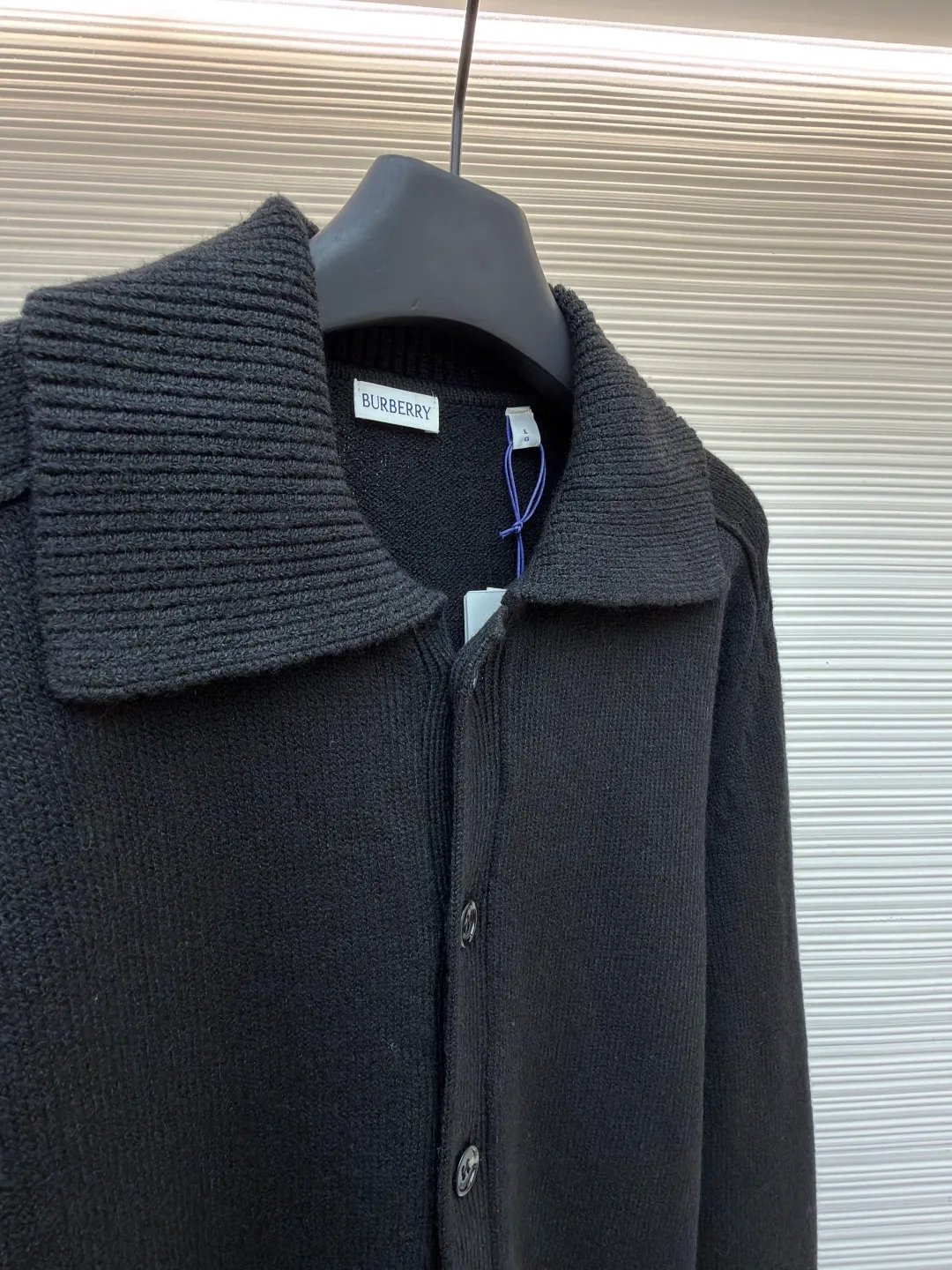 Burberry lapel rib knitted cashmere sweater ●Original version: purchased and developed by 11575 ●Item number: 1682226-B15 ●Fabric: wool blended fabric ●Technology: knitted ●Color: black ●Version: fitted version ●Weight: about 600 grams ●Size: S-M-L-XL ●Description: This black knitted cardigan is knitted with high-count worsted wool yarn. The main body is built using four-flat stitch technology, which gives the fabric good elasticity and shapeability, while forming a fine and tight texture. The ribbed lapel weaving process is used at the neckline, and a combination of different needle types is used to create a crisp collar profile. The rib structure can be freely expanded and contracted according to the wearing status to fit the neck line. The placket adopts inlaid buttonhole technology and is matched with matte resin buttons of the same color. The buttons and the body are fixed by hand-stitching, which is strong and beautiful. The brand logo patch on the lower side of the body is processed by a hot-pressing bonding process and fits seamlessly with the knitted fabric. The overall cut is a slightly loose shoulder-drop version, combined with three-dimensional darting technology, which ensures wearing comfort while creating clean lines. Every knitting node is manually inspected to ensure the uniformity and integrity of the knitted texture. The overall wiring is straight and delicate, the fabric is comfortable and soft, and the color is consistent without color difference. It can be matched with the same style to create a fashionable look and control various occasions. Customized accessories, complete with three standards, same style for men and women!