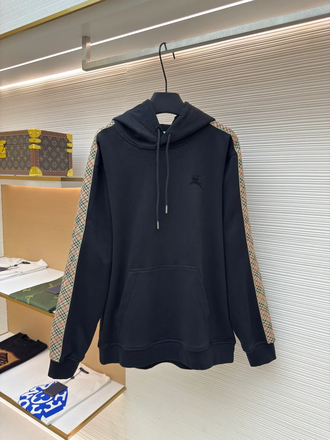 BURBERRY Ribbon trim hooded pullover sweatshirt ●Authentic product: Purchased and developed by 6239 ●Item number: 1680511-B15 ●Fabric: single-sided fish scale fabric ●Technology: selvedge production ●Version: fitted version ●Weight: about 895 grams ●Size: S-M-L-XL ●Description: A single-sided fish-scale cloth fabric woven with cotton as the base. The front is a smooth knitted surface, and the skin-contacting surface is formed into three-dimensional terry by the floating thread knitting technology of the knitting machine, which increases the fluffiness and has a delicate touch. The terry structure absorbs a large amount of water and evaporates quickly, so it is not easy to loosen and deform after repeated washing. By actively interfering with the shrinkage potential of cotton fibers, the fabric is able to transition from changeable to stable, improving dimensional stability while being less prone to deformation and wrinkles. The monochrome flat embroidery on the chest uses the high-precision calculation system of the computer embroidery machine to control the coordinated operation of the machine head, needle bar, and thread spool. The fabric frame moves accurately in the horizontal and vertical directions to form a stitch track. The upper and lower thread tensions are adjusted to ensure that the stitches are smooth and free of floating threads, forming a fine pattern with an error of ±0.1mm. The overall wiring is straight and delicate, the fabric is comfortable and soft, and the color is consistent without color difference. It can be matched with the same style to create a fashionable look and control various occasions. Customized accessories, complete with three standards, same style for men and women!