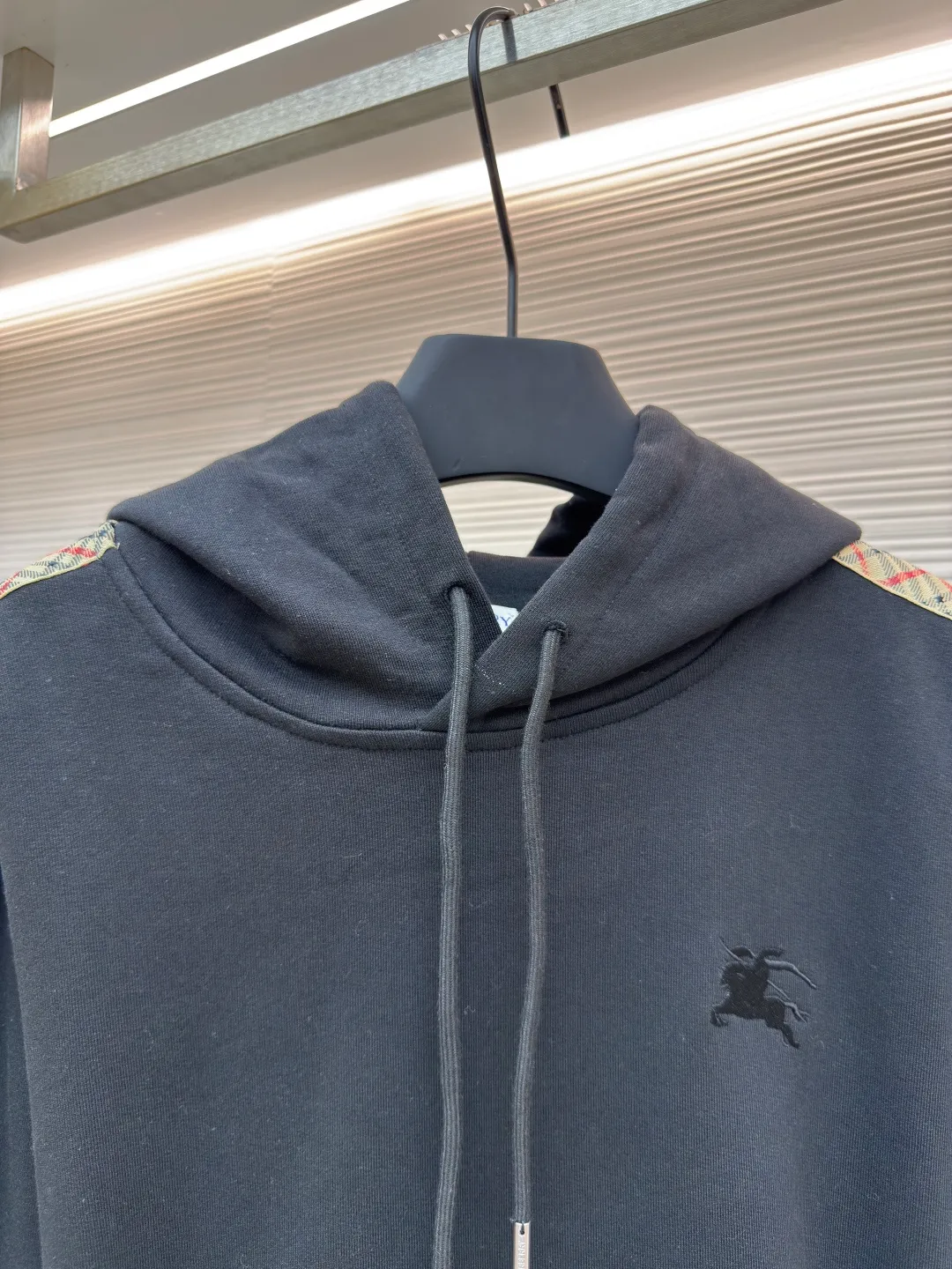 BURBERRY Ribbon trim hooded pullover sweatshirt ●Authentic product: Purchased and developed by 6239 ●Item number: 1680511-B15 ●Fabric: single-sided fish scale fabric ●Technology: selvedge production ●Version: fitted version ●Weight: about 895 grams ●Size: S-M-L-XL ●Description: A single-sided fish-scale cloth fabric woven with cotton as the base. The front is a smooth knitted surface, and the skin-contacting surface is formed into three-dimensional terry by the floating thread knitting technology of the knitting machine, which increases the fluffiness and has a delicate touch. The terry structure absorbs a large amount of water and evaporates quickly, so it is not easy to loosen and deform after repeated washing. By actively interfering with the shrinkage potential of cotton fibers, the fabric is able to transition from changeable to stable, improving dimensional stability while being less prone to deformation and wrinkles. The monochrome flat embroidery on the chest uses the high-precision calculation system of the computer embroidery machine to control the coordinated operation of the machine head, needle bar, and thread spool. The fabric frame moves accurately in the horizontal and vertical directions to form a stitch track. The upper and lower thread tensions are adjusted to ensure that the stitches are smooth and free of floating threads, forming a fine pattern with an error of ±0.1mm. The overall wiring is straight and delicate, the fabric is comfortable and soft, and the color is consistent without color difference. It can be matched with the same style to create a fashionable look and control various occasions. Customized accessories, complete with three standards, same style for men and women!