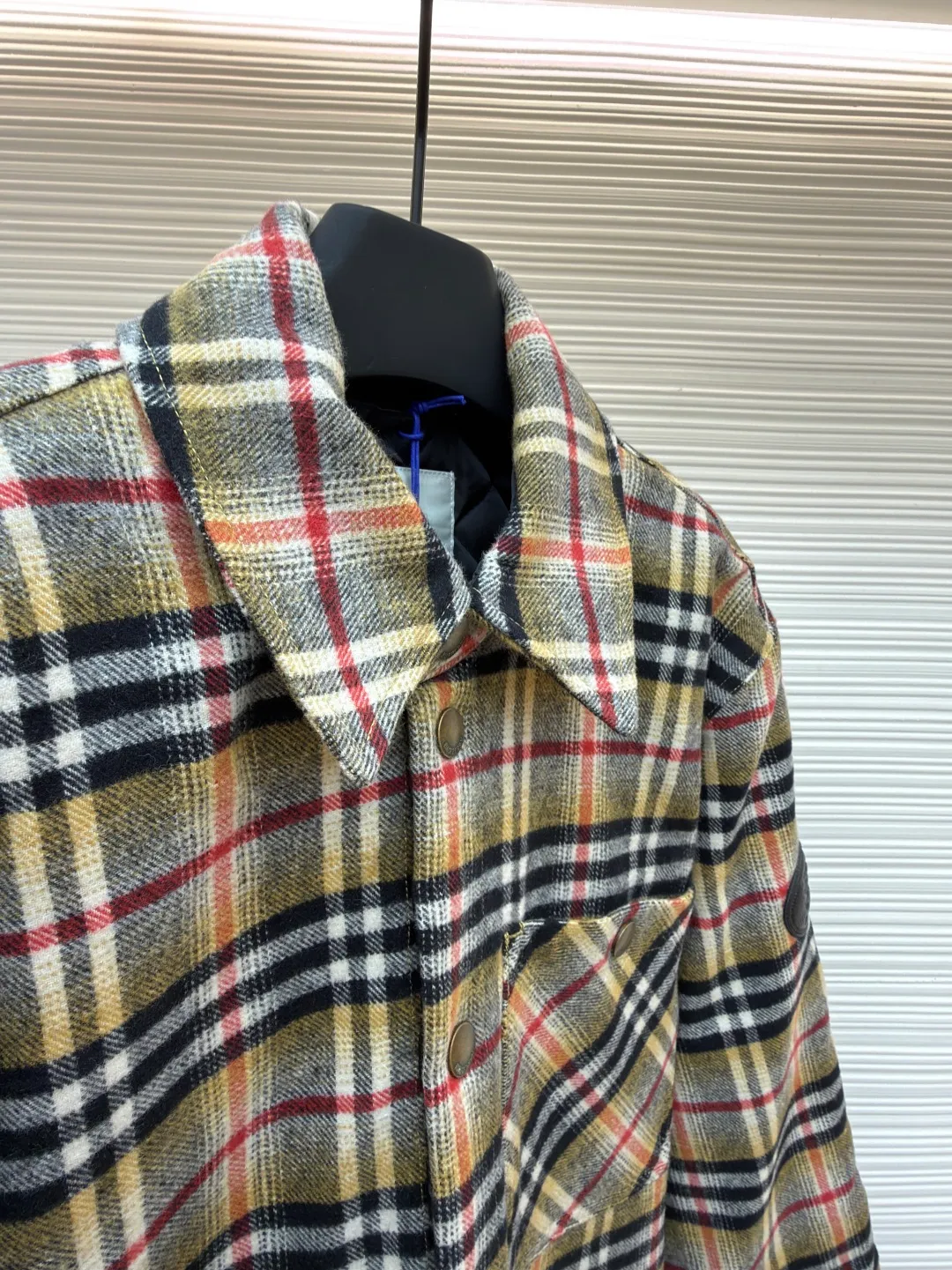 Burberry plaid wool lapel cotton coat ●Original version: Purchased and developed by 7353 ●Item number: 1681919-B40 ●Fabric: wool blended fabric ●Technology: Made on positioning cutting machine ●Color: Khaki ●Version: Fitted version ●Weight: about 800 grams ●Size: S-M-L-XL ●Description: This plaid shirt-style jacket is made of mixed-color wool blend fabric. It is combed to enhance the velvet feel and warmth, and the surface presents a natural variegated texture. The plaid pattern is based on khaki, with gray and red contrasting lines superimposed. The positioning printing process ensures that the plaid pattern is aligned when the pieces are spliced. The placket is made of vintage metal snaps, which are wear-resistant and have a thick texture; the left chest patch pocket is designed with diagonal splicing, and the bag mouth is reinforced with double-line sewing. The neckline is a classic lapel with seamed edges; the cuffs are single-button adjustable, and the inner lining is made of cotton of the same color to improve wearing comfort. The overall stitching density reaches 12 stitches/inch, and the double hemming process on the hem enhances durability. It is suitable for layering or single wear in autumn and winter. The overall wiring is straight and delicate, the fabric is comfortable and soft, and the color is consistent without color difference. It can be matched with the same style to create a fashionable look and control various occasions. Customized accessories, complete with three standards, same style for men and women!