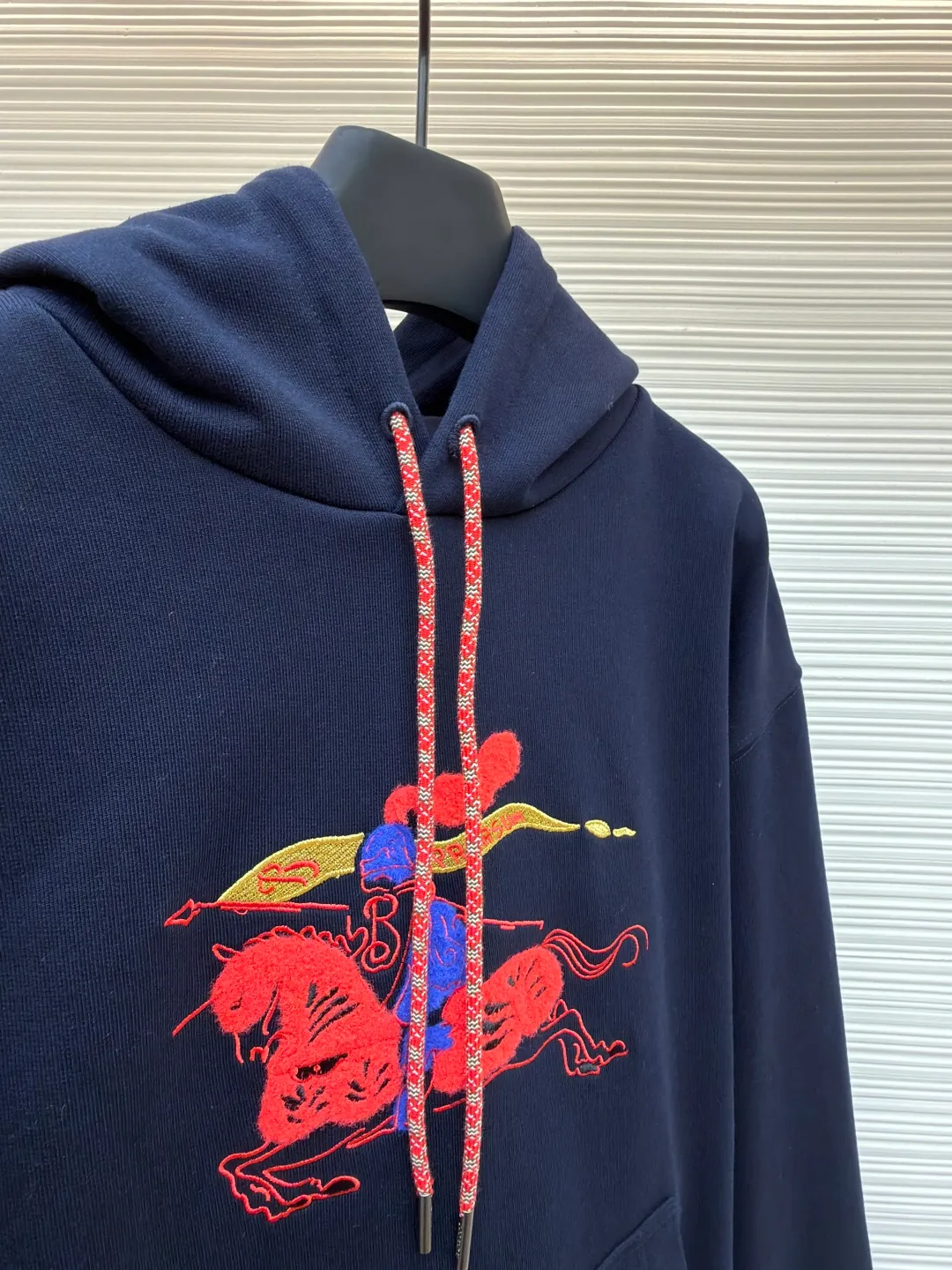 Burberry fleece horse embroidery hooded sweatshirt ●Original version: purchased and developed by 6239 ●Item number: 1682178-B05 ●Fabric: turned velvet cotton ●Technology: embroidery production ●Color: navy ●Version: fitted version ●Weight: about 1005 grams ●Size: XS-S-M-L ●Description: It adopts an inside-out velvet structure of 16-count double yarn on the top and 10-count yarn on the bottom, with a weight of up to 470g/㎡. It is matched with 21 double yarns and 1x1 rib, and the weight is 470g/㎡, ensuring that the cuffs, hem and other parts have unparalleled thickness and resilience, and the texture is unified and strong with the body. This is a special sweatshirt fabric that is ultra-heavy and high-density. Its inverted pile process means that the terry layer that is usually on the inside is turned over to the outside as the surface, and is finely brushed to directly present the appearance and feel of exceptionally rich, dense and soft pile, while the inside is relatively smooth. Metallic yarn embroidery: craftsmanship with plush effect, new season equestrian knight logo embroidery, and metallic yarn with a rich touch is the core of the design. During the embroidery process, a mixture of special yarns containing metallic threads is used, and through computer embroidery machine programming, the metallic yarns are integrated into specific parts of the pattern using stitching methods such as chain embroidery and tatami embroidery. On top of the traditional three-dimensional sense of embroidery, a shimmering metallic luster and a special cool touch are added, causing the classic logo pattern to produce local highlights under the light, showing a reshaped modern feel and a high-end customization-like sophistication, making it highly recognizable. The overall wiring is straight and delicate, the fabric is comfortable and soft, and the color is consistent without color difference. It can be matched with the same style to create a fashionable look and control various occasions. Customized accessories, complete with three standards, same style for men and women!