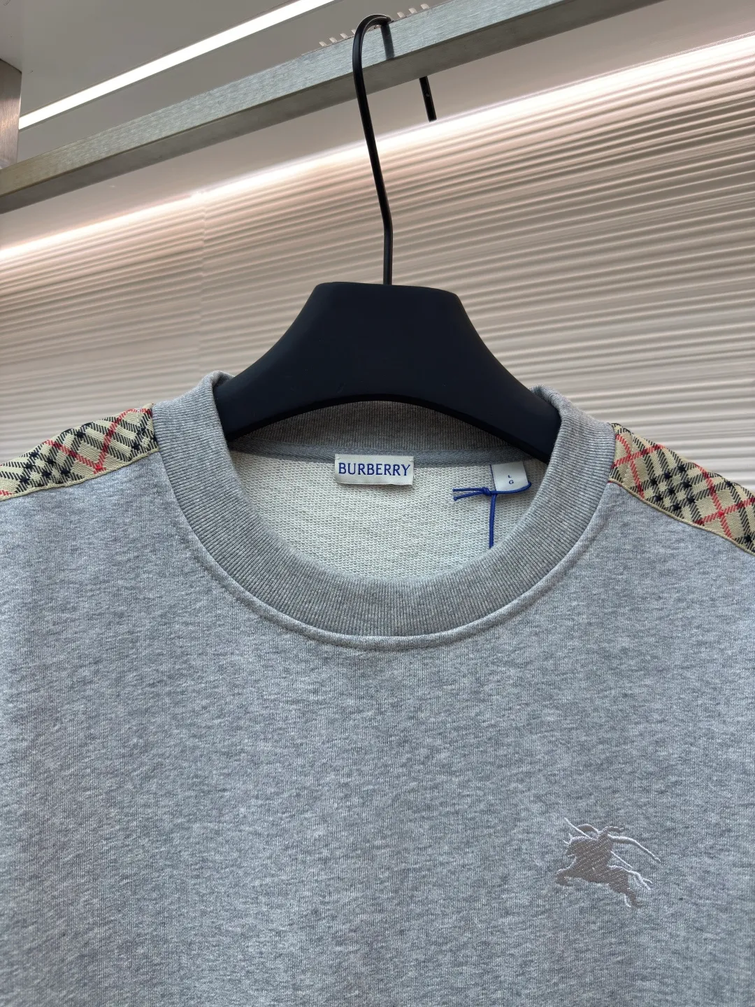 BURBERRY webbing trim round neck sweatshirt ●Authentic product: purchased and developed by 6155 ●Item number: 1680512-A85 ●Fabric: single-sided fish scale fabric ●Technology: selvedge production ●Version: fitted version ●Weight: about 645 grams ●Size: S-M-L-XL ●Description: A single-sided fish-scale cloth fabric woven with cotton as the base. The front is a smooth knitted surface, and the skin-contacting surface is formed into three-dimensional terry by the floating thread knitting technology of the knitting machine, which increases the fluffiness and has a delicate touch. The terry structure absorbs a large amount of water and evaporates quickly, so it is not easy to loosen and deform after repeated washing. By actively interfering with the shrinkage potential of cotton fibers, the fabric is able to transition from changeable to stable, improving dimensional stability while being less prone to deformation and wrinkles. The monochrome flat embroidery on the chest uses the high-precision calculation system of the computer embroidery machine to control the coordinated operation of the machine head, needle bar, and thread spool. The fabric frame moves accurately in the horizontal and vertical directions to form a stitch track. The upper and lower thread tensions are adjusted to ensure that the stitches are smooth and free of floating threads, forming a fine pattern with an error of ±0.1mm. The overall wiring is straight and delicate, the fabric is comfortable and soft, and the color is consistent without color difference. It can be matched with the same style to create a fashionable look and control various occasions. Customized accessories, complete with three standards, same style for men and women!