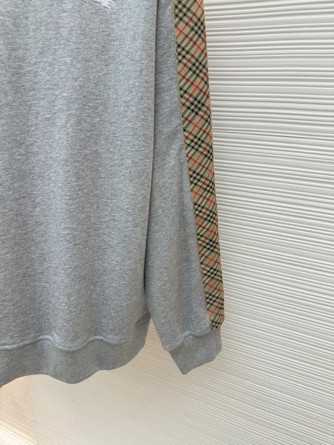 BURBERRY webbing trim round neck sweatshirt ●Authentic product: purchased and developed by 6155 ●Item number: 1680512-A85 ●Fabric: single-sided fish scale fabric ●Technology: selvedge production ●Version: fitted version ●Weight: about 645 grams ●Size: S-M-L-XL ●Description: A single-sided fish-scale cloth fabric woven with cotton as the base. The front is a smooth knitted surface, and the skin-contacting surface is formed into three-dimensional terry by the floating thread knitting technology of the knitting machine, which increases the fluffiness and has a delicate touch. The terry structure absorbs a large amount of water and evaporates quickly, so it is not easy to loosen and deform after repeated washing. By actively interfering with the shrinkage potential of cotton fibers, the fabric is able to transition from changeable to stable, improving dimensional stability while being less prone to deformation and wrinkles. The monochrome flat embroidery on the chest uses the high-precision calculation system of the computer embroidery machine to control the coordinated operation of the machine head, needle bar, and thread spool. The fabric frame moves accurately in the horizontal and vertical directions to form a stitch track. The upper and lower thread tensions are adjusted to ensure that the stitches are smooth and free of floating threads, forming a fine pattern with an error of ±0.1mm. The overall wiring is straight and delicate, the fabric is comfortable and soft, and the color is consistent without color difference. It can be matched with the same style to create a fashionable look and control various occasions. Customized accessories, complete with three standards, same style for men and women!