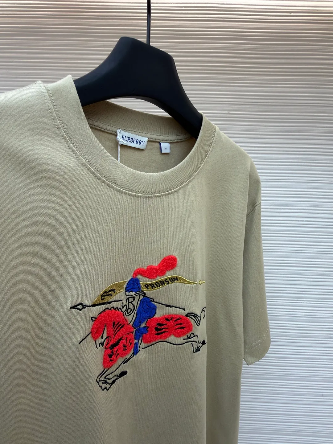 Burberry fleece pony round neck short sleeves ●Original version: Purchased and developed for 4850 ●Item number: 1682161-A05 ●Fabric: pure cotton plain weave ●Technology: embroidery production ●Color: khaki ●Version: fitted version ●Weight: about 290g ●Size: XS-S-M-L ●Description: Made of 15S fine cotton plain weave, 230g; matching 32S double yarn rack thread, 340g. Fine cotton fabrics usually have better moisture absorption, breathability, wear resistance, and are also softer and smoother. Vintage fine cotton fabric is a relatively thick cotton fabric that has been carefully processed and treated to have excellent texture and performance. It feels soft and comfortable and fits the skin very well when worn. Craftsmanship with plush effect, new season equestrian knight logo embroidery, and metallic yarns with a rich touch are the core of the design. During the embroidery process, special yarns containing metallic threads are mixed and programmed through a computer embroidery machine to integrate the metallic yarns into specific parts of the pattern using stitching methods such as chain embroidery and tatami embroidery. On top of the traditional three-dimensional sense of embroidery, a shimmering metallic luster and a special cool touch are added, causing the classic logo pattern to produce local highlights under light, showing a reshaped modern sense and a high-end customization-like sophistication, which is highly recognizable. The overall wiring is straight and delicate, the fabric is comfortable and soft, and the color is consistent without color difference. It can be matched with the same style to create a fashionable look and control various occasions. Customized accessories, complete with three standards, same style for men and women!