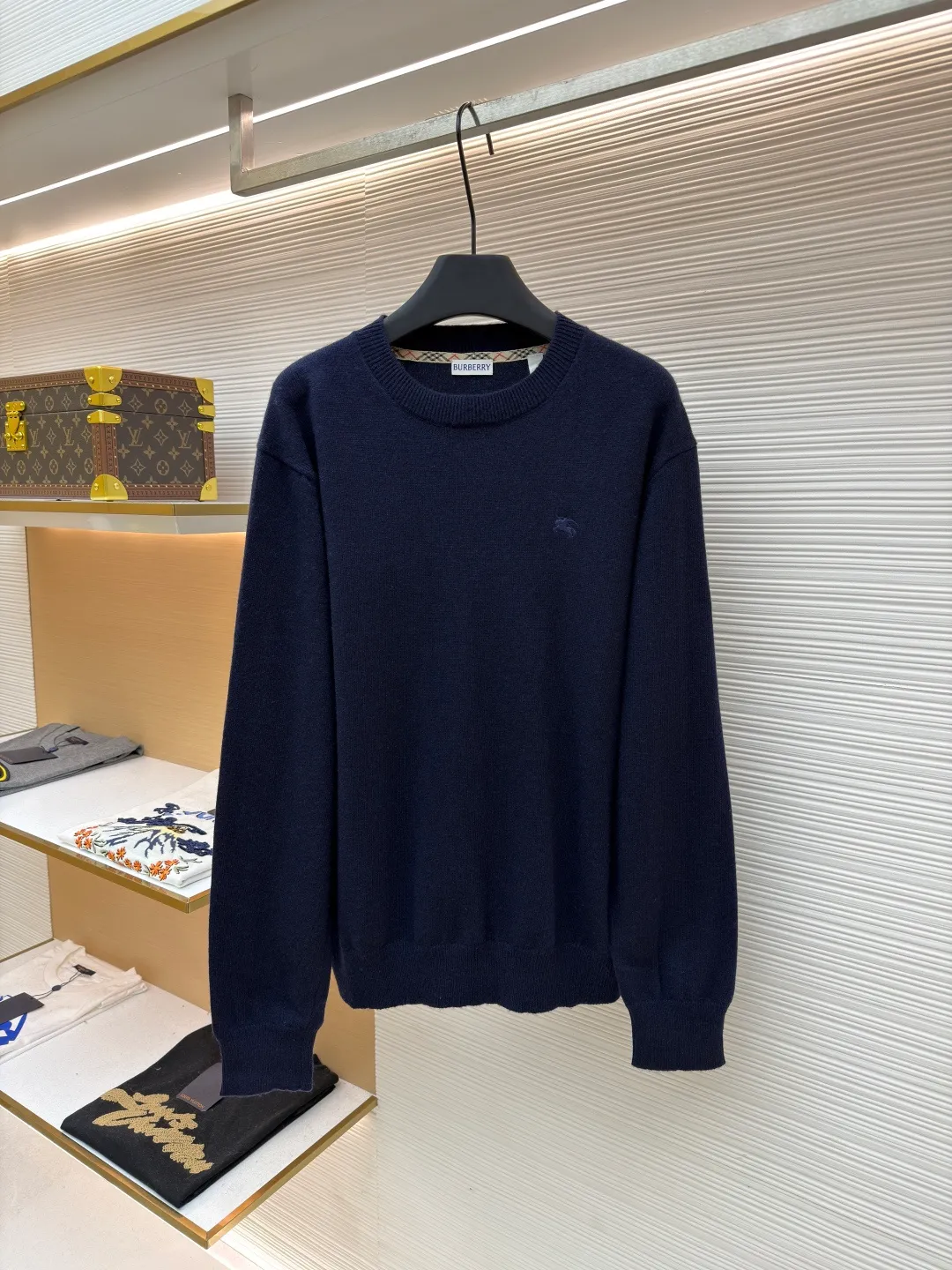 Burberry embroidered crew neck sweater ●Original version: Purchased and developed for 1499 ●Item number: 1681780-B25 ●Fabric: wool blended fabric ●Technology: knitted ●Color: navy ●Version: Fitted version ●Weight: about 465 grams ●Size: S-M-L-XL ●Description: Cashmere is used as the main body to dominate the feel, warmth and lightness of the fabric, while providing an unparalleled wearing experience. A small amount of polyamide and Lycra are added to enhance the overall durability and pilling resistance. An invisible support network is woven into the soft cashmere, and it also has a certain amount of elasticity to better fit the curves of the human body and allow it to be retracted and retracted freely. The ribbed decorative parts of the collar and cuffs are made of blended fabrics of the same proportion, which further enhances the texture and wearing experience. Due to the characteristics of the sweater fabric, it is stretched just right when stretching the frame, and then a hot-melt liner is used under the wool fabric piece to provide it with a certain temporary stable support to prevent it from shrinking after removal, causing pattern distortion, wrinkles and stitch dents. The high-precision calculation program system of the computer embroidery machine controls the movement of the embroidery frame in the X/Y direction, while the needle shuttles up and down, embroidering according to the set path, automatically completing thread trimming, thread jumping and other actions to form a stitch track, automatically adjusting the upper and lower thread tension to ensure that the stitches are smooth and free of floating threads, forming a war horse pattern with an error of ±0.1mm. Add detergent and preliminarily rinse the bulk goods at a water temperature of about 35 degrees to remove impurities during the production process, and then use protease to gently digest the hairiness on the surface to reduce the tendency of pilling from the root, improve the hand feel, retain softness, and eliminate irritation. Finally, after dehydration and drying, the dimensional and shape stability is improved. The overall wiring is straight and delicate, the fabric is comfortable and soft, and the color is consistent without color difference. It can be matched with the same style to create a fashionable look and control various occasions. Customized accessories, complete with three standards, same style for men and women!