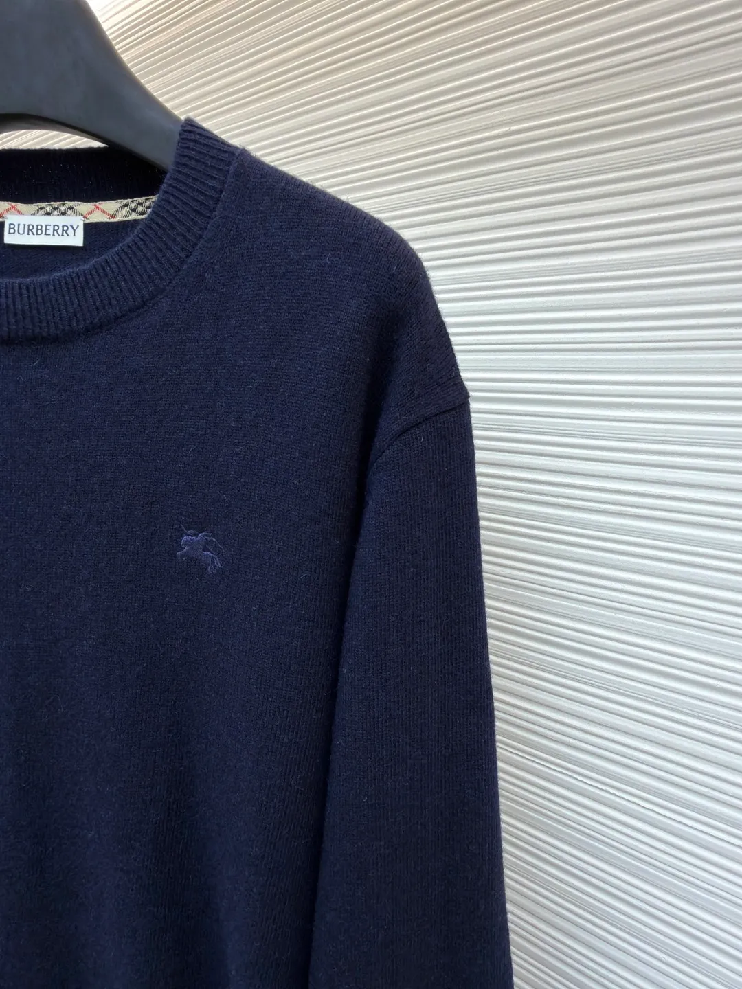 Burberry embroidered crew neck sweater ●Original version: Purchased and developed for 1499 ●Item number: 1681780-B25 ●Fabric: wool blended fabric ●Technology: knitted ●Color: navy ●Version: Fitted version ●Weight: about 465 grams ●Size: S-M-L-XL ●Description: Cashmere is used as the main body to dominate the feel, warmth and lightness of the fabric, while providing an unparalleled wearing experience. A small amount of polyamide and Lycra are added to enhance the overall durability and pilling resistance. An invisible support network is woven into the soft cashmere, and it also has a certain amount of elasticity to better fit the curves of the human body and allow it to be retracted and retracted freely. The ribbed decorative parts of the collar and cuffs are made of blended fabrics of the same proportion, which further enhances the texture and wearing experience. Due to the characteristics of the sweater fabric, it is stretched just right when stretching the frame, and then a hot-melt liner is used under the wool fabric piece to provide it with a certain temporary stable support to prevent it from shrinking after removal, causing pattern distortion, wrinkles and stitch dents. The high-precision calculation program system of the computer embroidery machine controls the movement of the embroidery frame in the X/Y direction, while the needle shuttles up and down, embroidering according to the set path, automatically completing thread trimming, thread jumping and other actions to form a stitch track, automatically adjusting the upper and lower thread tension to ensure that the stitches are smooth and free of floating threads, forming a war horse pattern with an error of ±0.1mm. Add detergent and preliminarily rinse the bulk goods at a water temperature of about 35 degrees to remove impurities during the production process, and then use protease to gently digest the hairiness on the surface to reduce the tendency of pilling from the root, improve the hand feel, retain softness, and eliminate irritation. Finally, after dehydration and drying, the dimensional and shape stability is improved. The overall wiring is straight and delicate, the fabric is comfortable and soft, and the color is consistent without color difference. It can be matched with the same style to create a fashionable look and control various occasions. Customized accessories, complete with three standards, same style for men and women!