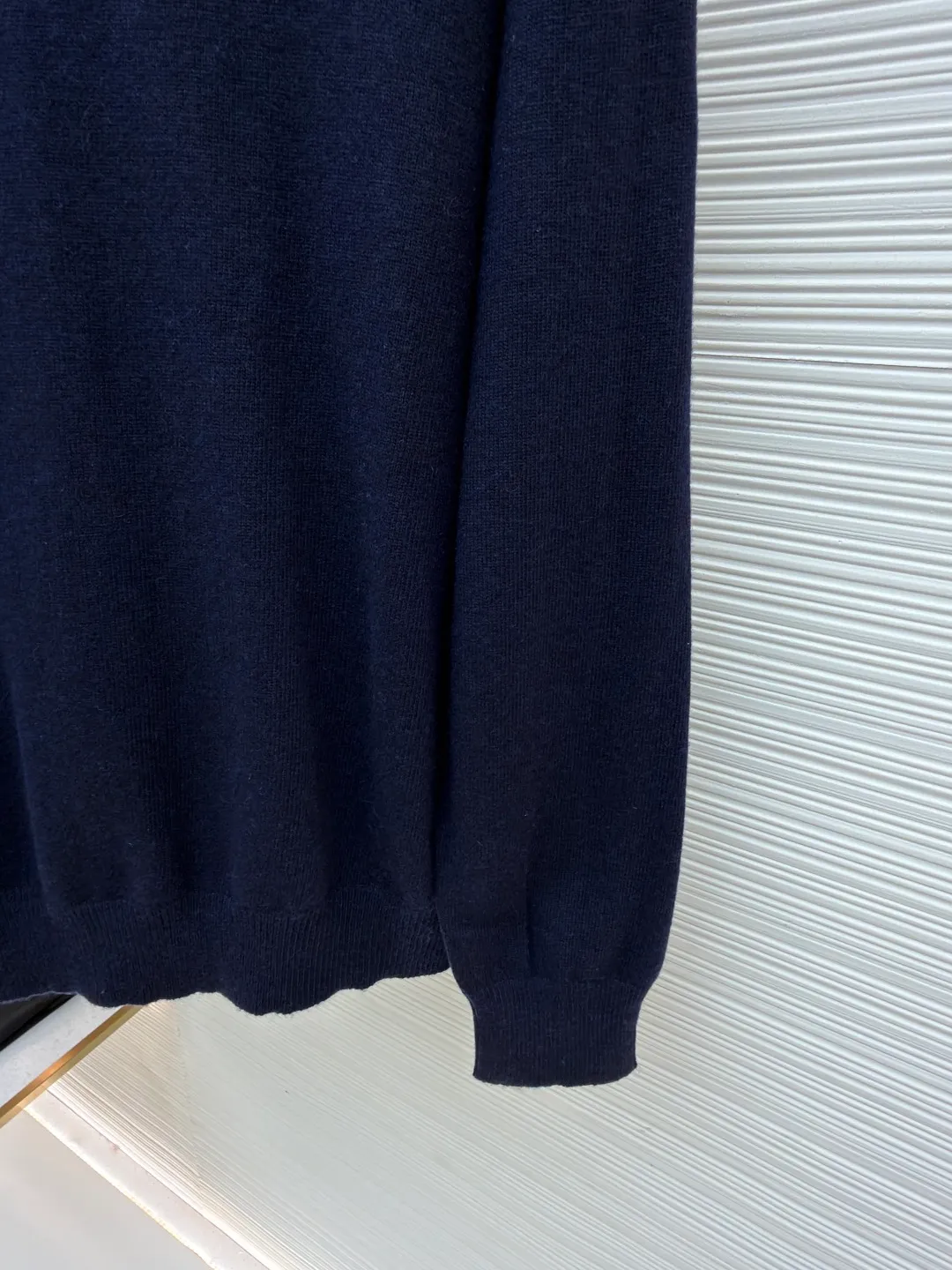 Burberry embroidered crew neck sweater ●Original version: Purchased and developed for 1499 ●Item number: 1681780-B25 ●Fabric: wool blended fabric ●Technology: knitted ●Color: navy ●Version: Fitted version ●Weight: about 465 grams ●Size: S-M-L-XL ●Description: Cashmere is used as the main body to dominate the feel, warmth and lightness of the fabric, while providing an unparalleled wearing experience. A small amount of polyamide and Lycra are added to enhance the overall durability and pilling resistance. An invisible support network is woven into the soft cashmere, and it also has a certain amount of elasticity to better fit the curves of the human body and allow it to be retracted and retracted freely. The ribbed decorative parts of the collar and cuffs are made of blended fabrics of the same proportion, which further enhances the texture and wearing experience. Due to the characteristics of the sweater fabric, it is stretched just right when stretching the frame, and then a hot-melt liner is used under the wool fabric piece to provide it with a certain temporary stable support to prevent it from shrinking after removal, causing pattern distortion, wrinkles and stitch dents. The high-precision calculation program system of the computer embroidery machine controls the movement of the embroidery frame in the X/Y direction, while the needle shuttles up and down, embroidering according to the set path, automatically completing thread trimming, thread jumping and other actions to form a stitch track, automatically adjusting the upper and lower thread tension to ensure that the stitches are smooth and free of floating threads, forming a war horse pattern with an error of ±0.1mm. Add detergent and preliminarily rinse the bulk goods at a water temperature of about 35 degrees to remove impurities during the production process, and then use protease to gently digest the hairiness on the surface to reduce the tendency of pilling from the root, improve the hand feel, retain softness, and eliminate irritation. Finally, after dehydration and drying, the dimensional and shape stability is improved. The overall wiring is straight and delicate, the fabric is comfortable and soft, and the color is consistent without color difference. It can be matched with the same style to create a fashionable look and control various occasions. Customized accessories, complete with three standards, same style for men and women!