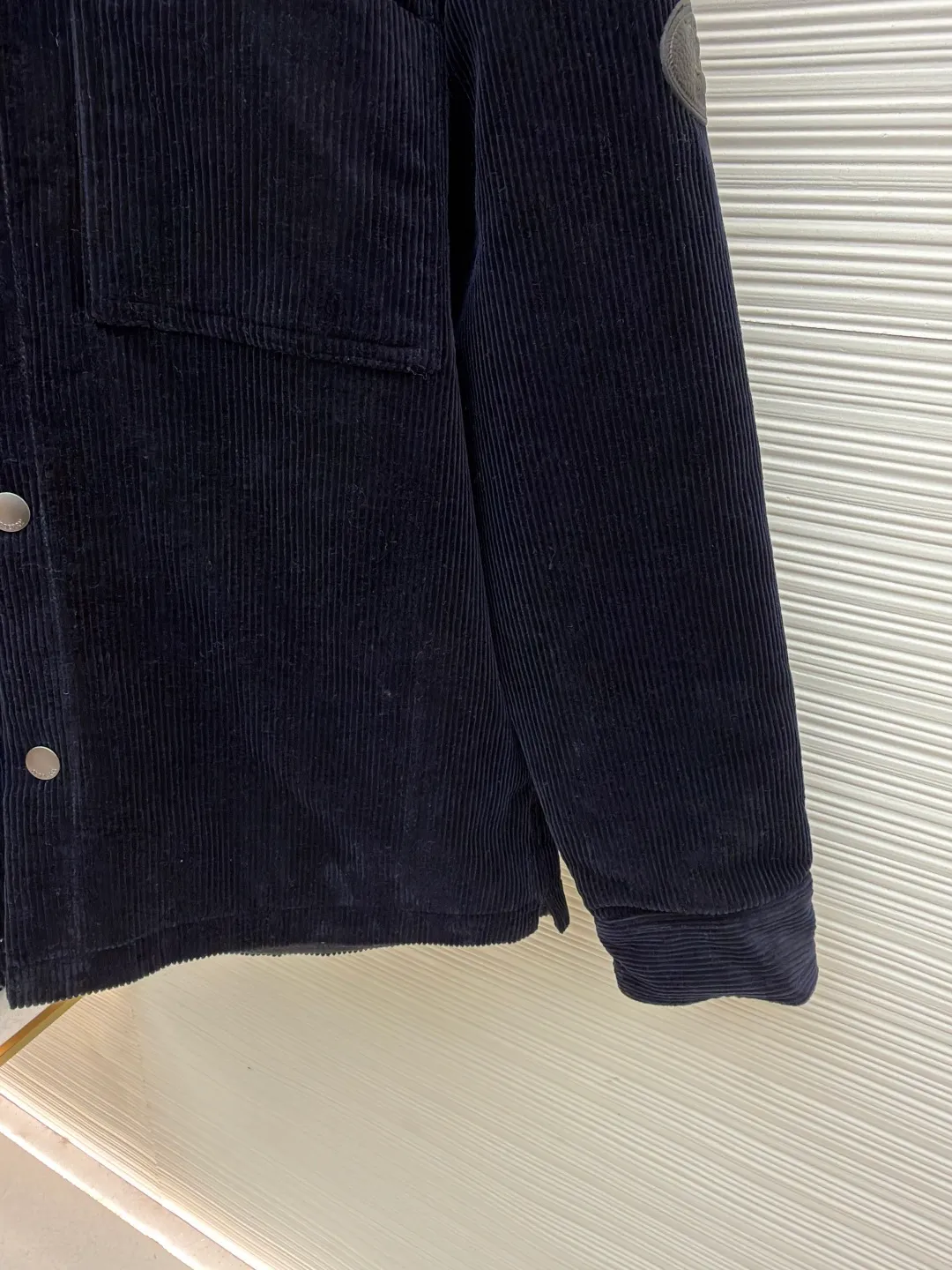 Burberry solid color lapel snap-fastening cotton jacket ●Original version: purchased and developed by 8766 ●Item number: 1681956-B40 ●Fabric: 100% cotton ●Technology: Made on positioning cutting machine ●Color: navy blue ●Version: fitted version ●Weight: about 940 grams ●Size: S-M-L-XL ●Description: This LV navy corduroy jacket is made of 8 wide corduroy fabrics, which are washed and distressed. The velvet strips are full and soft to the touch, while maintaining wrinkle resistance. The body of the garment adopts a whole-piece cutting process to ensure that the vertical texture of the corduroy is consistent and uninterrupted, and the splicing is sewn with invisible embedded clips, making the appearance more tidy. The chest patch pocket is made of double-layer quilted fabric, and the edges of the bag flap are edged with the same material. It is equipped with matte metal snap buttons, and the buckle surface is sandblasted to give a low-key texture. The ribs on the cuffs and hem are made of the same fabric and are elastic to fit the body shape. The left arm decorative plate is made of embossed + vegetable tanned leather splicing, and the brand logo is concealed and three-dimensional. The inner lining is lined with thin nylon interlining to improve the smoothness of putting on and taking off. The overall stitching stitches are evenly spaced (8 stitches per centimeter), taking into account the retro texture and practical durability. The overall wiring is straight and delicate, the fabric is comfortable and soft, and the color is consistent without color difference. It can be matched with the same style to create a fashionable look and control various occasions. Customized accessories, complete with three standards, same style for men and women!