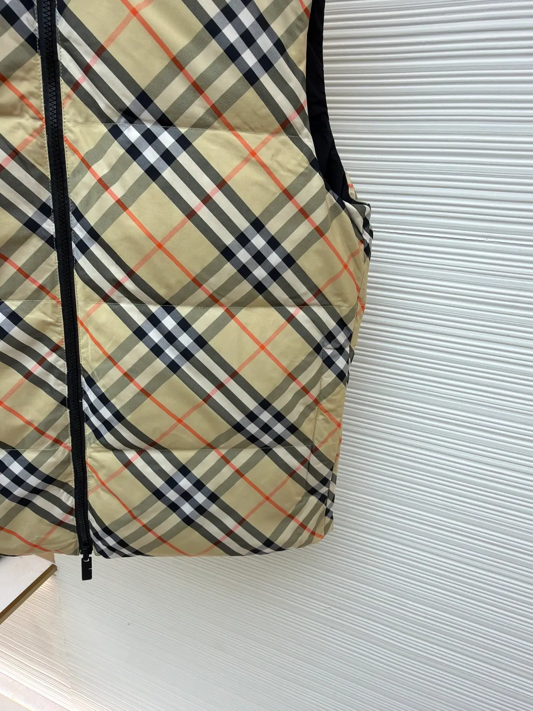 Burberry plaid down vest ●Original version: Purchased and developed by 7064 ●Item number: 1681079-C55 ●Fabric: goose down fabric ●Technology: made on positioning cutting machine ●Version: fitted version ●Weight: about 655 grams ●Size: XS-S-M-L-XL ●Description: Say goodbye to the weight of winter and embrace the warmth with a light attitude. BURBERRY's plaid down vest is crafted from protective nylon fabric and filled with high-quality 90 new national standard white duck down, giving you a warm experience of cloud-like wrapping without fear of severe cold. When the hood is not needed, it can be neatly tucked into the back of the collar, maintaining the smooth silhouette and simple style of the vest, making it perfect for both business and leisure occasions. When the weather changes, you can easily unfold it and you will instantly have a protective hood to cope with sudden wind, rain or cold. This kind of "invisible" protection means that style never compromises due to function. The front chest is decorated with a silicone plaque of the knight's logo from the archives of the 1980s, showing off its extraordinary status in a low-key manner. The two-way zipper opens and closes smoothly, and the side zipper pockets and drawstring hem details combine practical functionality with modern style. Concealed hooded design. The overall wiring is straight and delicate, the fabric is comfortable and soft, and the color is consistent without color difference. It can be matched with the same style to create a fashionable look and control various occasions. Customized accessories, complete with three standards, same style for men and women!