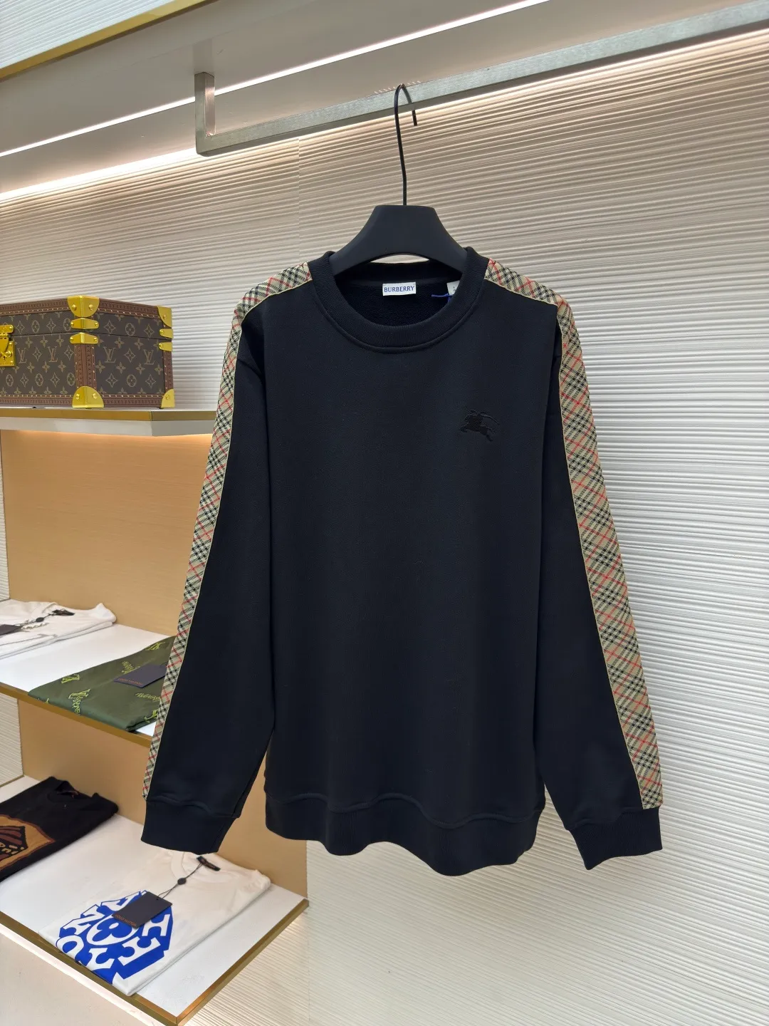 BURBERRY webbing trim round neck sweatshirt ●Authentic product: purchased and developed by 6143 ●Item number: 1680513-A85 ●Fabric: single-sided fish scale fabric ●Technology: selvedge production ●Version: fitted version ●Weight: about 666 grams ●Size: S-M-L-XL ●Description: A single-sided fish-scale cloth fabric woven with cotton as the base. The front is a smooth knitted surface, and the skin-contacting surface is formed into three-dimensional terry by the floating thread knitting technology of the knitting machine, which increases the fluffiness and has a delicate touch. The terry structure absorbs a large amount of water and evaporates quickly, so it is not easy to loosen and deform after repeated washing. By actively interfering with the shrinkage potential of cotton fibers, the fabric is able to transition from changeable to stable, improving dimensional stability while being less prone to deformation and wrinkles. The monochrome flat embroidery on the chest uses the high-precision calculation system of the computer embroidery machine to control the coordinated operation of the machine head, needle bar, and thread spool. The fabric frame moves accurately in the horizontal and vertical directions to form a stitch track. The upper and lower thread tensions are adjusted to ensure that the stitches are smooth and free of floating threads, forming a fine pattern with an error of ±0.1mm. The overall wiring is straight and delicate, the fabric is comfortable and soft, and the color is consistent without color difference. It can be matched with the same style to create a fashionable look and control various occasions. Customized accessories, complete with three standards, same style for men and women!