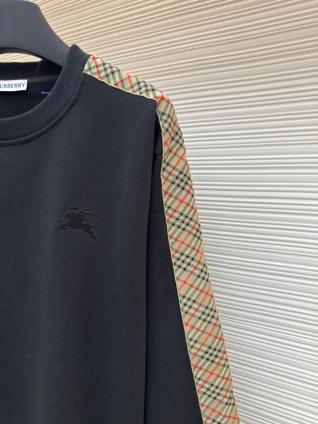 BURBERRY webbing trim round neck sweatshirt ●Authentic product: purchased and developed by 6143 ●Item number: 1680513-A85 ●Fabric: single-sided fish scale fabric ●Technology: selvedge production ●Version: fitted version ●Weight: about 666 grams ●Size: S-M-L-XL ●Description: A single-sided fish-scale cloth fabric woven with cotton as the base. The front is a smooth knitted surface, and the skin-contacting surface is formed into three-dimensional terry by the floating thread knitting technology of the knitting machine, which increases the fluffiness and has a delicate touch. The terry structure absorbs a large amount of water and evaporates quickly, so it is not easy to loosen and deform after repeated washing. By actively interfering with the shrinkage potential of cotton fibers, the fabric is able to transition from changeable to stable, improving dimensional stability while being less prone to deformation and wrinkles. The monochrome flat embroidery on the chest uses the high-precision calculation system of the computer embroidery machine to control the coordinated operation of the machine head, needle bar, and thread spool. The fabric frame moves accurately in the horizontal and vertical directions to form a stitch track. The upper and lower thread tensions are adjusted to ensure that the stitches are smooth and free of floating threads, forming a fine pattern with an error of ±0.1mm. The overall wiring is straight and delicate, the fabric is comfortable and soft, and the color is consistent without color difference. It can be matched with the same style to create a fashionable look and control various occasions. Customized accessories, complete with three standards, same style for men and women!