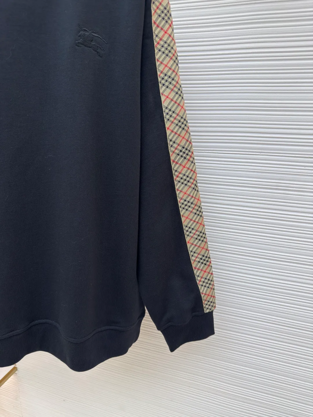 BURBERRY webbing trim round neck sweatshirt ●Authentic product: purchased and developed by 6143 ●Item number: 1680513-A85 ●Fabric: single-sided fish scale fabric ●Technology: selvedge production ●Version: fitted version ●Weight: about 666 grams ●Size: S-M-L-XL ●Description: A single-sided fish-scale cloth fabric woven with cotton as the base. The front is a smooth knitted surface, and the skin-contacting surface is formed into three-dimensional terry by the floating thread knitting technology of the knitting machine, which increases the fluffiness and has a delicate touch. The terry structure absorbs a large amount of water and evaporates quickly, so it is not easy to loosen and deform after repeated washing. By actively interfering with the shrinkage potential of cotton fibers, the fabric is able to transition from changeable to stable, improving dimensional stability while being less prone to deformation and wrinkles. The monochrome flat embroidery on the chest uses the high-precision calculation system of the computer embroidery machine to control the coordinated operation of the machine head, needle bar, and thread spool. The fabric frame moves accurately in the horizontal and vertical directions to form a stitch track. The upper and lower thread tensions are adjusted to ensure that the stitches are smooth and free of floating threads, forming a fine pattern with an error of ±0.1mm. The overall wiring is straight and delicate, the fabric is comfortable and soft, and the color is consistent without color difference. It can be matched with the same style to create a fashionable look and control various occasions. Customized accessories, complete with three standards, same style for men and women!