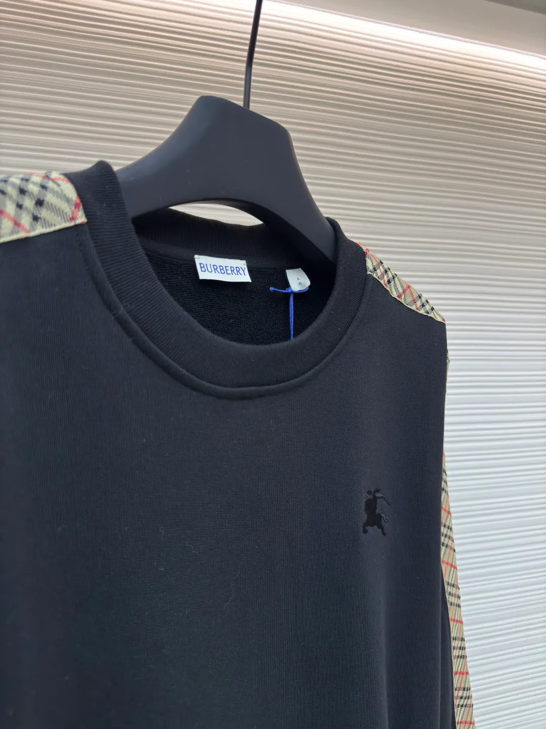 BURBERRY webbing trim round neck sweatshirt ●Authentic product: purchased and developed by 6143 ●Item number: 1680513-A85 ●Fabric: single-sided fish scale fabric ●Technology: selvedge production ●Version: fitted version ●Weight: about 666 grams ●Size: S-M-L-XL ●Description: A single-sided fish-scale cloth fabric woven with cotton as the base. The front is a smooth knitted surface, and the skin-contacting surface is formed into three-dimensional terry by the floating thread knitting technology of the knitting machine, which increases the fluffiness and has a delicate touch. The terry structure absorbs a large amount of water and evaporates quickly, so it is not easy to loosen and deform after repeated washing. By actively interfering with the shrinkage potential of cotton fibers, the fabric is able to transition from changeable to stable, improving dimensional stability while being less prone to deformation and wrinkles. The monochrome flat embroidery on the chest uses the high-precision calculation system of the computer embroidery machine to control the coordinated operation of the machine head, needle bar, and thread spool. The fabric frame moves accurately in the horizontal and vertical directions to form a stitch track. The upper and lower thread tensions are adjusted to ensure that the stitches are smooth and free of floating threads, forming a fine pattern with an error of ±0.1mm. The overall wiring is straight and delicate, the fabric is comfortable and soft, and the color is consistent without color difference. It can be matched with the same style to create a fashionable look and control various occasions. Customized accessories, complete with three standards, same style for men and women!