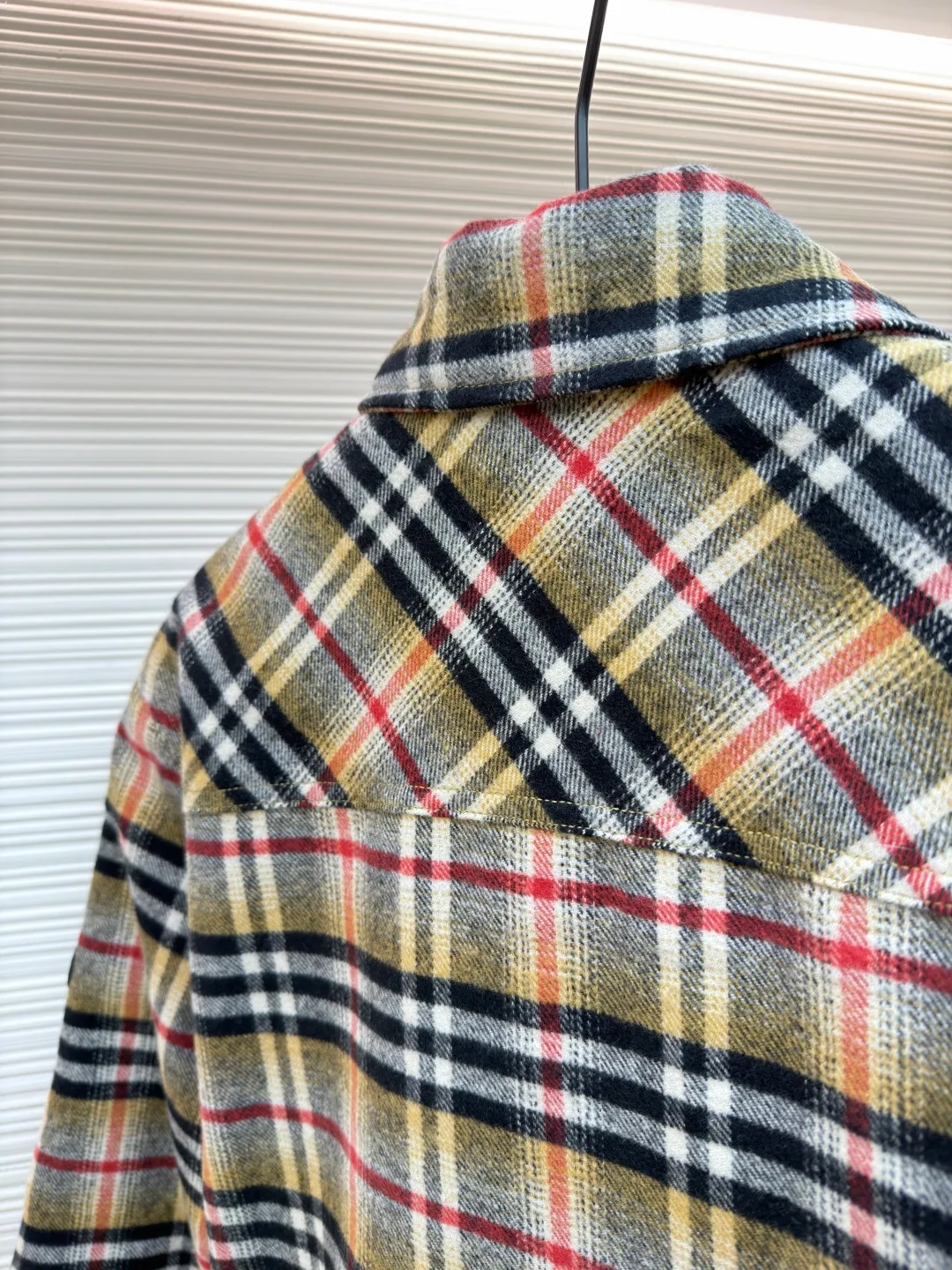 Burberry plaid wool lapel cotton coat ●Original version: Purchased and developed by 7353 ●Item number: 1681919-B40 ●Fabric: wool blended fabric ●Technology: Made on positioning cutting machine ●Color: Khaki ●Version: Fitted version ●Weight: about 800 grams ●Size: S-M-L-XL ●Description: This plaid shirt-style jacket is made of mixed-color wool blend fabric. It is combed to enhance the velvet feel and warmth, and the surface presents a natural variegated texture. The plaid pattern is based on khaki, with gray and red contrasting lines superimposed. The positioning printing process ensures that the plaid pattern is aligned when the pieces are spliced. The placket is made of vintage metal snaps, which are wear-resistant and have a thick texture; the left chest patch pocket is designed with diagonal splicing, and the bag mouth is reinforced with double-line sewing. The neckline is a classic lapel with seamed edges; the cuffs are single-button adjustable, and the inner lining is made of cotton of the same color to improve wearing comfort. The overall stitching density reaches 12 stitches/inch, and the double hemming process on the hem enhances durability. It is suitable for layering or single wear in autumn and winter. The overall wiring is straight and delicate, the fabric is comfortable and soft, and the color is consistent without color difference. It can be matched with the same style to create a fashionable look and control various occasions. Customized accessories, complete with three standards, same style for men and women!