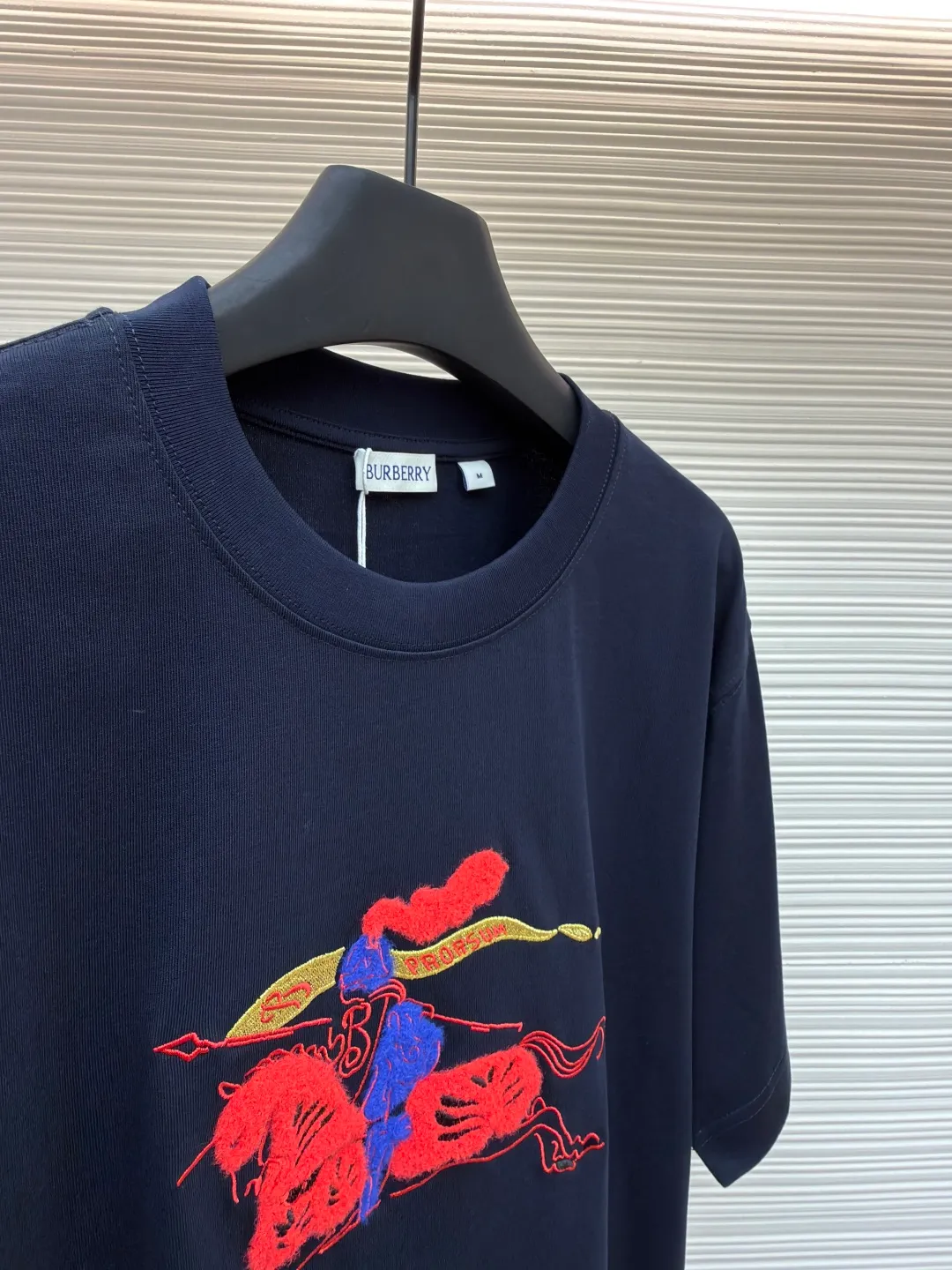 Burberry fleece pony round neck short sleeves ●Original version: Purchased and developed for 4850 ●Item number: 1682163-A05 ●Fabric: pure cotton plain weave ●Technology: embroidery production ●Color: navy blue ●Version: fitted version ●Weight: about 265g ●Size: XS-S-M-L ●Description: Made of 15S fine cotton plain weave, 230g; matching 32S double yarn rack thread, 340g. Fine cotton fabrics usually have better moisture absorption, breathability, wear resistance, and are also softer and smoother. Vintage fine cotton fabric is a relatively thick cotton fabric that has been carefully processed and treated to have excellent texture and performance. It feels soft and comfortable and fits the skin very well when worn. Craftsmanship with plush effect, new season equestrian knight logo embroidery, and metallic yarns with a rich touch are the core of the design. During the embroidery process, special yarns containing metallic threads are mixed and programmed through a computer embroidery machine to integrate the metallic yarns into specific parts of the pattern using stitching methods such as chain embroidery and tatami embroidery. On top of the traditional three-dimensional sense of embroidery, a shimmering metallic luster and a special cool touch are added, causing the classic logo pattern to produce local highlights under light, showing a reshaped modern sense and a high-end customization-like sophistication, which is highly recognizable. The overall wiring is straight and delicate, the fabric is comfortable and soft, and the color is consistent without color difference. It can be matched with the same style to create a fashionable look and control various occasions. Customized accessories, complete with three standards, same style for men and women!