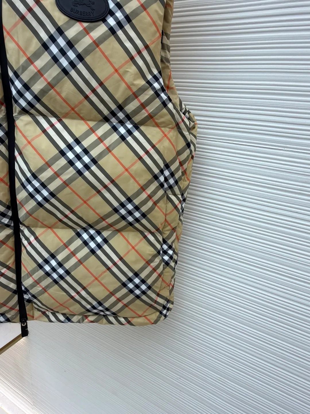Burberry plaid logo down vest ●Original version: Purchased and developed by 7031 ●Item number: 1681078-C55 ●Fabric: goose down fabric ●Technology: made on positioning cutting machine ●Version: fitted version ●Weight: about 510 grams ●Size: XS-S-M-L-XL ●Description: Say goodbye to the weight of winter and embrace the warmth with a light attitude. BURBERRY's plaid down vest is crafted from protective nylon fabric and filled with high-quality 90 new national standard white duck down, giving you a warm experience of cloud-like wrapping without fear of severe cold. When the hood is not needed, it can be neatly tucked into the back of the collar, maintaining the smooth silhouette and simple style of the vest, making it perfect for both business and leisure occasions. When the weather changes, you can easily unfold it and you will instantly have a protective hood to cope with sudden wind, rain or cold. This kind of "invisible" protection means that style never compromises due to function. The front chest is decorated with a silicone plaque of the knight's logo from the archives of the 1980s, showing off its extraordinary status in a low-key manner. The two-way zipper opens and closes smoothly, and the side zipper pockets and drawstring hem details combine practical functionality with modern style. Concealed hooded design. The overall wiring is straight and delicate, the fabric is comfortable and soft, and the color is consistent without color difference. It can be matched with the same style to create a fashionable look and control various occasions. Customized accessories, complete with three standards, same style for men and women!