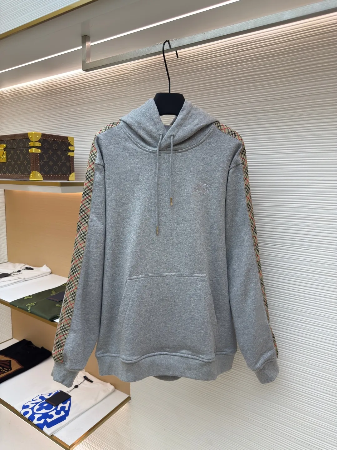 BURBERRY Ribbon trim hooded pullover sweatshirt ●Authentic product: Purchased and developed by 6239 ●Item number: 1680510-B15 ●Fabric: single-sided fish scale fabric ●Technology: selvedge production ●Version: fitted version ●Weight: about 855 grams ●Size: S-M-L-XL ●Description: A single-sided fish-scale cloth fabric woven with cotton as the base. The front is a smooth knitted surface, and the skin-contacting surface is formed into three-dimensional terry by the floating thread knitting technology of the knitting machine, which increases the fluffiness and has a delicate touch. The terry structure absorbs a large amount of water and evaporates quickly, so it is not easy to loosen and deform after repeated washing. By actively interfering with the shrinkage potential of cotton fibers, the fabric is able to transition from changeable to stable, improving dimensional stability while being less prone to deformation and wrinkles. The monochrome flat embroidery on the chest uses the high-precision calculation system of the computer embroidery machine to control the coordinated operation of the machine head, needle bar, and thread spool. The fabric frame moves accurately in the horizontal and vertical directions to form a stitch track. The upper and lower thread tensions are adjusted to ensure that the stitches are smooth and free of floating threads, forming a fine pattern with an error of ±0.1mm. The overall wiring is straight and delicate, the fabric is comfortable and soft, and the color is consistent without color difference. It can be matched with the same style to create a fashionable look and control various occasions. Customized accessories, complete with three standards, same style for men and women!