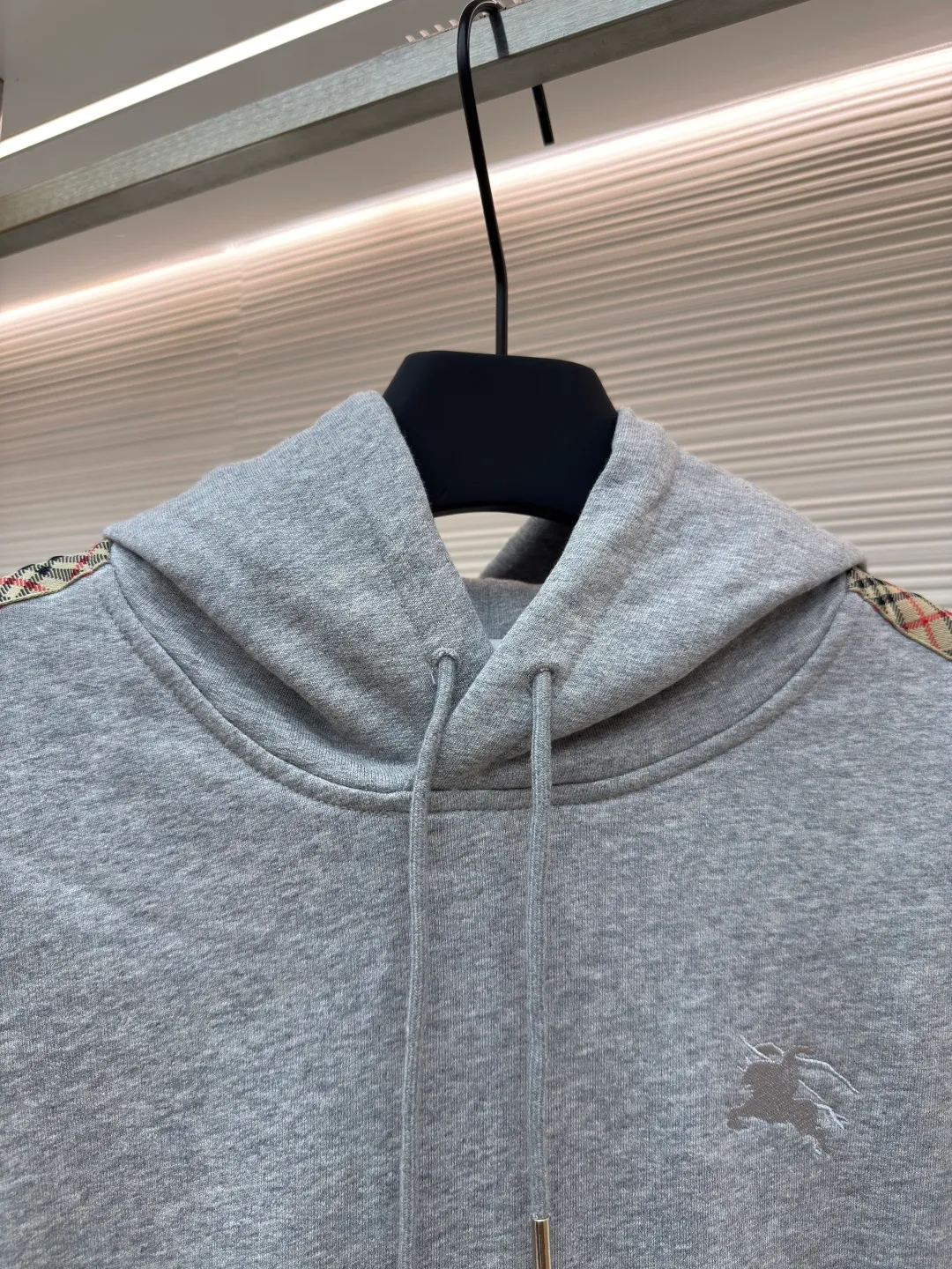 BURBERRY Ribbon trim hooded pullover sweatshirt ●Authentic product: Purchased and developed by 6239 ●Item number: 1680510-B15 ●Fabric: single-sided fish scale fabric ●Technology: selvedge production ●Version: fitted version ●Weight: about 855 grams ●Size: S-M-L-XL ●Description: A single-sided fish-scale cloth fabric woven with cotton as the base. The front is a smooth knitted surface, and the skin-contacting surface is formed into three-dimensional terry by the floating thread knitting technology of the knitting machine, which increases the fluffiness and has a delicate touch. The terry structure absorbs a large amount of water and evaporates quickly, so it is not easy to loosen and deform after repeated washing. By actively interfering with the shrinkage potential of cotton fibers, the fabric is able to transition from changeable to stable, improving dimensional stability while being less prone to deformation and wrinkles. The monochrome flat embroidery on the chest uses the high-precision calculation system of the computer embroidery machine to control the coordinated operation of the machine head, needle bar, and thread spool. The fabric frame moves accurately in the horizontal and vertical directions to form a stitch track. The upper and lower thread tensions are adjusted to ensure that the stitches are smooth and free of floating threads, forming a fine pattern with an error of ±0.1mm. The overall wiring is straight and delicate, the fabric is comfortable and soft, and the color is consistent without color difference. It can be matched with the same style to create a fashionable look and control various occasions. Customized accessories, complete with three standards, same style for men and women!