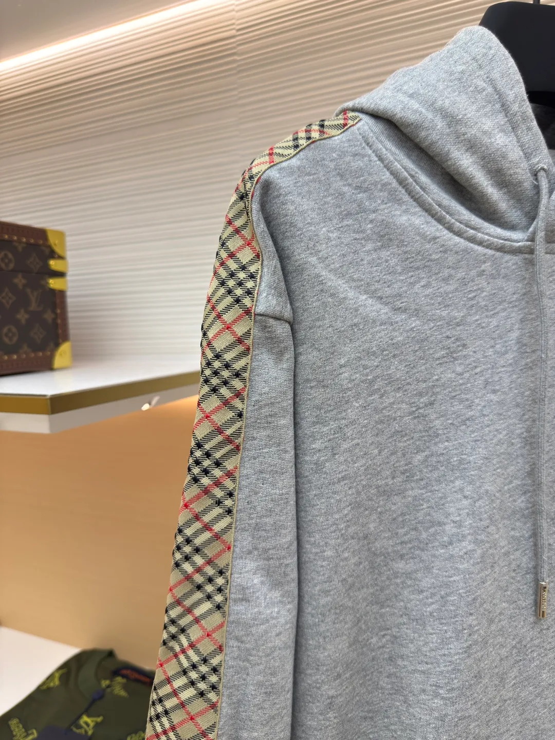 BURBERRY Ribbon trim hooded pullover sweatshirt ●Authentic product: Purchased and developed by 6239 ●Item number: 1680510-B15 ●Fabric: single-sided fish scale fabric ●Technology: selvedge production ●Version: fitted version ●Weight: about 855 grams ●Size: S-M-L-XL ●Description: A single-sided fish-scale cloth fabric woven with cotton as the base. The front is a smooth knitted surface, and the skin-contacting surface is formed into three-dimensional terry by the floating thread knitting technology of the knitting machine, which increases the fluffiness and has a delicate touch. The terry structure absorbs a large amount of water and evaporates quickly, so it is not easy to loosen and deform after repeated washing. By actively interfering with the shrinkage potential of cotton fibers, the fabric is able to transition from changeable to stable, improving dimensional stability while being less prone to deformation and wrinkles. The monochrome flat embroidery on the chest uses the high-precision calculation system of the computer embroidery machine to control the coordinated operation of the machine head, needle bar, and thread spool. The fabric frame moves accurately in the horizontal and vertical directions to form a stitch track. The upper and lower thread tensions are adjusted to ensure that the stitches are smooth and free of floating threads, forming a fine pattern with an error of ±0.1mm. The overall wiring is straight and delicate, the fabric is comfortable and soft, and the color is consistent without color difference. It can be matched with the same style to create a fashionable look and control various occasions. Customized accessories, complete with three standards, same style for men and women!