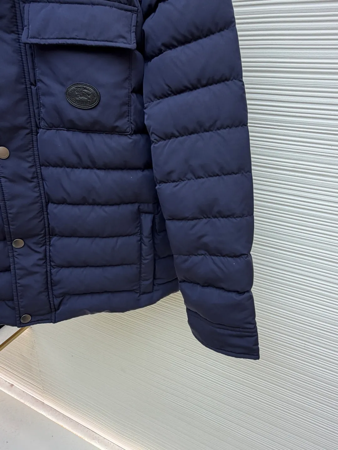 Burberry light leather label down jacket ●Original version: Purchased and developed by 6125 ●Item number: 1681879-C95 ●Fabric: white duck down fabric ●Technology: mechanical down filling ●Color: navy blue ●Version: fitted version ●Weight: about 780 grams ●Size: S-M-L-XL ●Description: High-density nylon taffeta: Made of 100D nylon fabric, density ≥230T, durable Slightly calendered (showing low-key luster), and fluorine-free waterproof coating (DWR) to ensure water repellency while maintaining breathability (refer to the slightly wrinkled texture and stiffness of the fabric in the picture) Anti-velvet gallbladder: Use high-density polyester gallbladder cloth (such as gallbladder silk spinning) above 300T to ensure that the down does not rip through velvet, and is light and thin without affecting the fluffiness. Filling 900-fill white duck down (85%-90% down content) ensures a full three-dimensional effect but not too bloated. It uses YKK brand No. 5 nylon zipper (matte dark gray/black, close to the fabric). The zipper teeth are fine-toothed and flat-toothed. The puller is simple and square. The brand logo is etched on the surface. The outside of the zipper needs to be seamed. 1.5cm wide windproof placket made of the same color fabric (double-layered, with thin cotton strips sandwiched inside to increase stiffness). The cuffs are fake two-piece design (the outer layer is folded cuffs, and the inner layer is ribbed). The outer cuffs are equipped with 2 metal buttons (diameter 12mm, the same series as the pocket snaps), with a spacing of 3cm. The buttonholes are hand-made keyholes (double-line seaming, precise aperture). They are made of first-layer calfskin (thickness 0.8-mm). The leather surface is matte aniline dyed and the edges are warped. Oil edge treatment (thickness 0.3mm, round and smooth, color consistent with leather label). The brand pattern (knight logo + text) on the surface of the leather label adopts embossing + hot stamping/silvering technology. The overall wiring is straight and delicate, the fabric is comfortable and soft, and the color is consistent without color difference. It can be matched with the same style to create a fashionable look and control various occasions. Customized accessories, complete with three labels, same style for men and women!