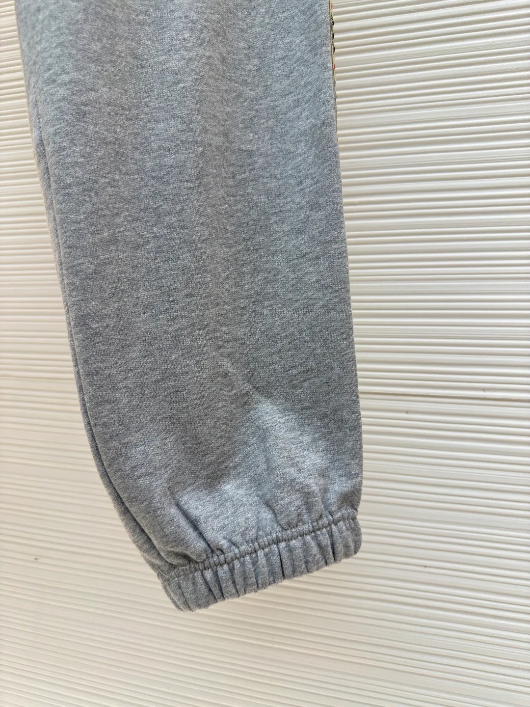 BURBERRY plaid webbing embroidered sweatpants ●Authentic product: purchased and developed by 5202 ●Item number: 1680515-A95 ●Fabric: single-sided fish scale fabric ●Technology: selvage production ●Version: fitted version ●Weight: about 705 grams ●Size: S-M-L-XL ●Description: A single-sided fish-scale cloth fabric woven with cotton as the base. The front is a smooth knitted surface, and the skin-contacting surface is formed into three-dimensional terry by the floating thread knitting technology of the knitting machine, which increases the fluffiness and has a delicate touch. The terry structure absorbs a large amount of water and evaporates quickly, so it is not easy to loosen and deform after repeated washing. By actively interfering with the shrinkage potential of cotton fibers, the fabric is able to transition from changeable to stable, improving dimensional stability while being less prone to deformation and wrinkles. The monochrome flat embroidery on the chest uses the high-precision calculation system of the computer embroidery machine to control the coordinated operation of the machine head, needle bar, and thread spool. The fabric frame moves accurately in the horizontal and vertical directions to form a stitch track. The upper and lower thread tensions are adjusted to ensure that the stitches are smooth and free of floating threads, forming a fine pattern with an error of ±0.1mm. The overall wiring is straight and delicate, the fabric is comfortable and soft, and the color is consistent without color difference. It can be matched with the same style to create a fashionable look and control various occasions. Customized accessories, complete with three standards, same style for men and women!