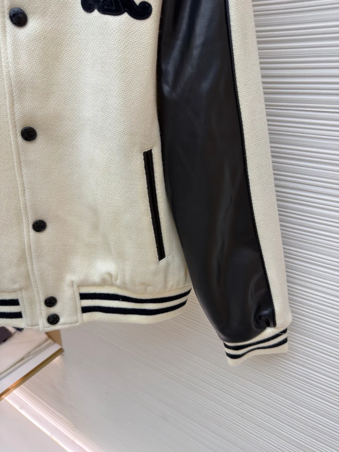 Celine buttoned cowhide embroidered baseball jacket ●Original version: purchased and developed by 13599 ●Item number: 1682009-C95 ●Fabric: genuine leather fabric ●Technology: embroidery production ●Color: beige ●Version: fitted version ●Weight: about 1165 grams ●Size: 46-48-50-52 ●Description: The main body is made of off-white slub knitted fabric, which is stiff and soft to the touch; the edges of the sleeves and pockets are made of matte black leather, spliced with precision stitching, and the edges are roughened to enhance the texture. The collar, cuffs, and hem are all made of black and white contrasting rib knitting, and the elastic hemming process ensures a good fit. There are 6 black metal snap buttons on the front, which open and close smoothly and are not easy to oxidize. The brand's iconic "double C" logo on the left chest uses flocking embroidery technology to make it three-dimensional and full. The pockets have an oblique invisible design, and the inner lining is made of cotton fabric of the same color. The wiring is even and fine, and the overall craftsmanship takes into account both retro style and high-end texture. The overall wiring is straight and delicate, the fabric is comfortable and soft, and the color is consistent without color difference. It can be matched with the same style to create a fashionable look and control various occasions. Customized accessories, complete with three standards, same style for men and women!