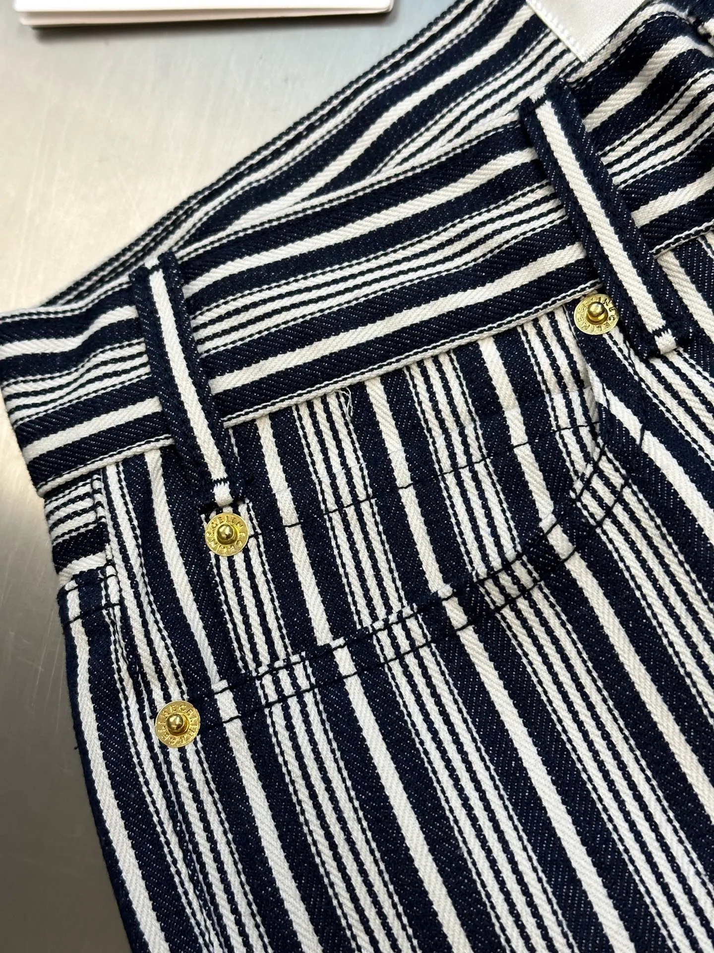 🅿️500 Celine striped straight trousers. These CELINE striped jeans cleverly combine retro elegance with modern street style. The crisp and stylish straight-leg trousers are matched with navy blue and off-white pinstripe texture, which visually makes the legs more slender. The golden metal buttons and zipper pullers on the front are engraved with the CELINE brand logo, showing exquisite style in the details.  The waistband adopts a classic five-pocket design, and the front and rear pockets are equipped with metal rivets, which combines practicality and design. The trousers are made of thick and crisp high-quality denim cotton. The fabric has a three-dimensional and clear texture. It is both durable and more textured. It is suitable for daily commuting or urban casual wear.  size：s m l