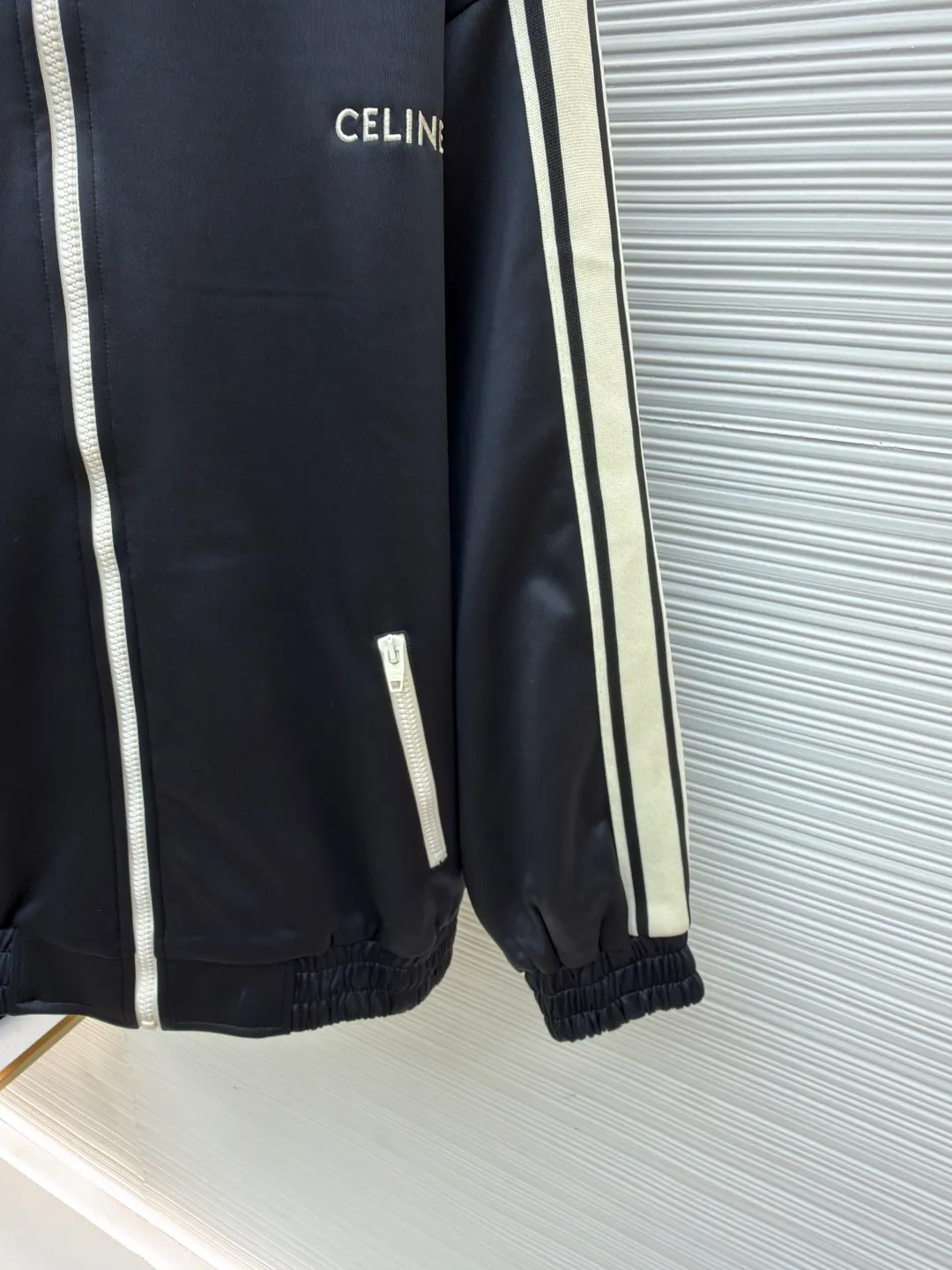Celine side webbing splicing jacket ●Original version: Purchased and developed by 6909 ●Item number: 1681407-B70 ●Fabric: pure cotton fabric ●Technology: ribbon production ●Color: black ●Version: fitted version ●Weight: about 780 grams ●Size: XS-S-M-L ●Description: This jacket is made of high-quality smooth fabric, with a crisp texture and good drape. The stand-up collar design is equipped with a metal zipper, which is smooth and durable, and easy to open and close. The white stripes on the side of the sleeves are made of precision splicing technology, which naturally connects with the black body, and the lines are straight and smooth. The "CELINE" brand logo on the body is three-dimensional embroidery, the stitching is fine and even, and the brand is highly recognizable. The pockets on both sides are equipped with zippers, which are practical and enhance the overall texture. The rib design on the cuffs and hem has excellent elasticity and fits the body shape. From fabric selection to embroidery, splicing and zipper craftsmanship, every detail demonstrates the brand's strict control over quality, integrating sports style with high-end fashion craftsmanship, with both practicality and fashion. The overall wiring is straight and delicate, the fabric is comfortable and soft, and the color is consistent without color difference. It can be matched with the same style to create a fashionable look and control various occasions. Customized accessories, complete with three standards, same style for men and women!