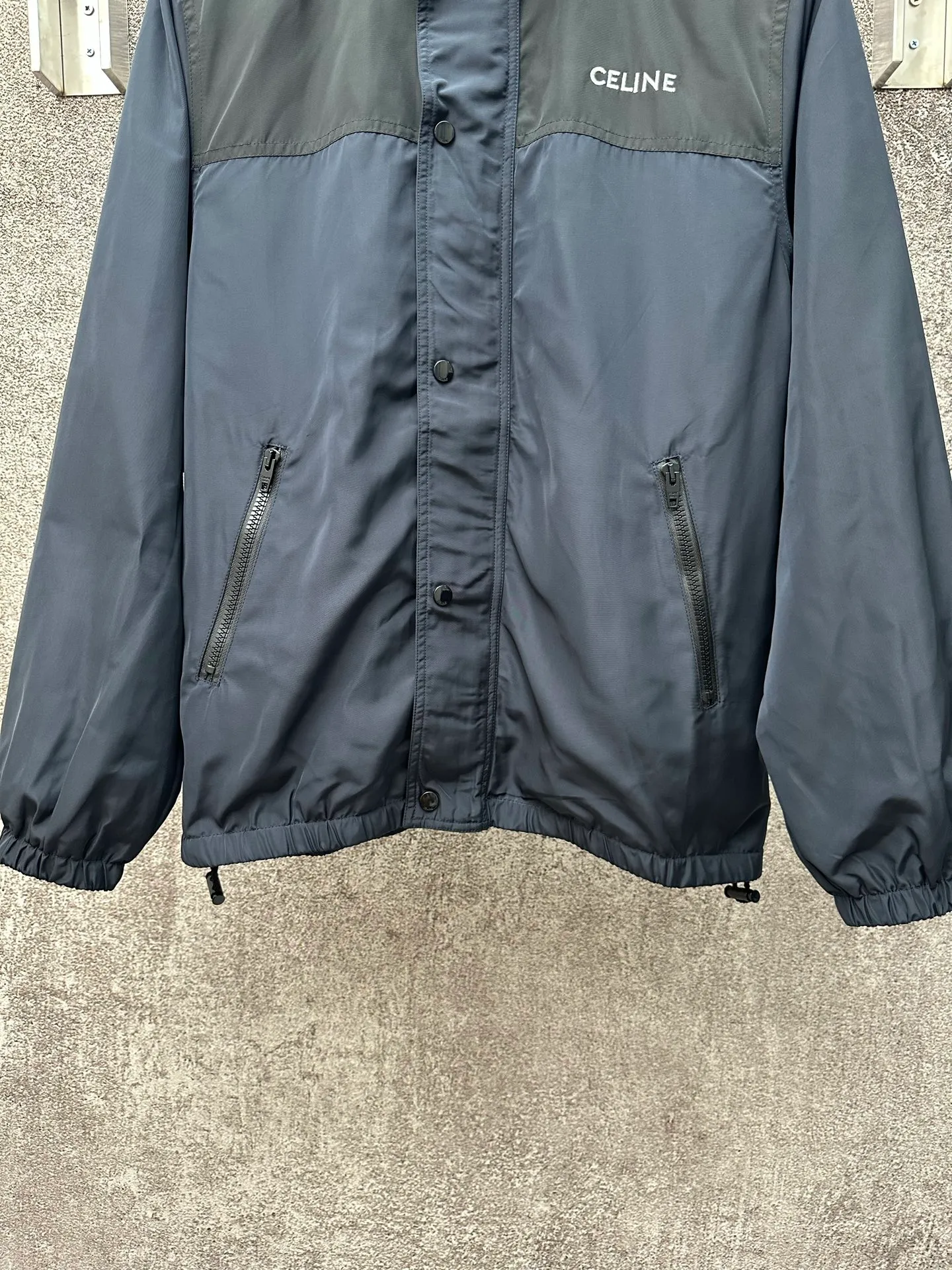 🅿️600 CELINE embroidered windbreaker Fabric selection: Oxford fabric made of 100% polyester fiber. The fiber properties have good toughness, and the lattice-like weave structure of Oxford cloth makes the fabric structure tight, very resistant to pulling and abrasion, and at the same time it has certain water-repellent properties. The density of polyester fiber itself is not high. While providing high strength, it maintains a relatively light weight and is easy to wear.  Technology: The computer embroidery machine is set to extremely high stitch density, and the fabric and backing are tightly fixed on the frame of the embroidery machine with even and just the right tension. The double-axis linear guide drives the embroidery frame, and the frame moving accuracy can reach 0.01mm/P, ensuring precise positioning and the embroidery pattern completely covering the base fabric.  The zipper and 6 snap-buttons engraved with CELINE provide double protection. Accessories: One-to-one customized snap-buttons, One-to-one customized elastic buckles, One-to-one customized zipper pullers, SIZE: 46 48 50 52